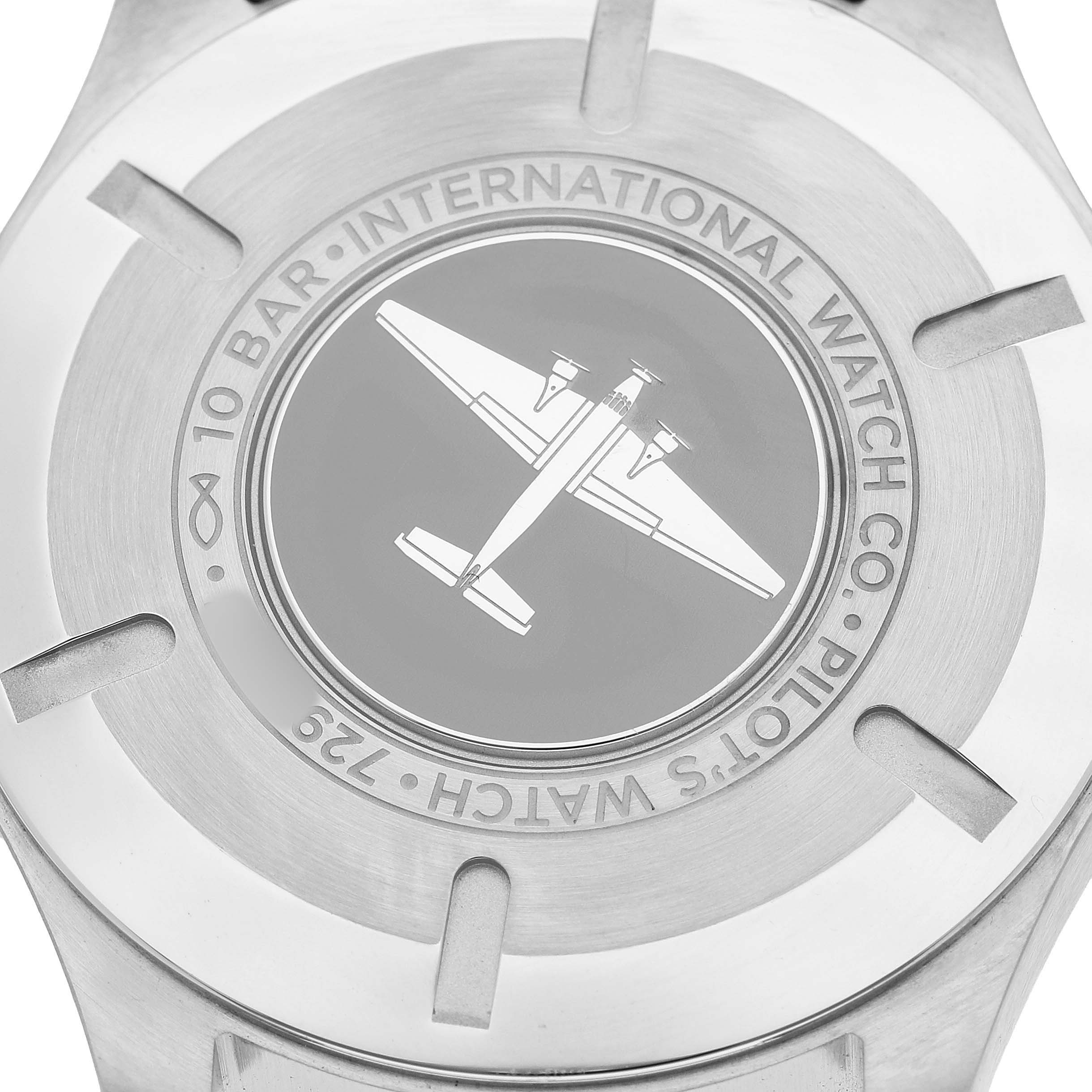 The image shows the back of an IWC Pilot IW328204 Men's Stainless Steel Blue Dial model watch, featuring an engraved airplane design and brand markings.