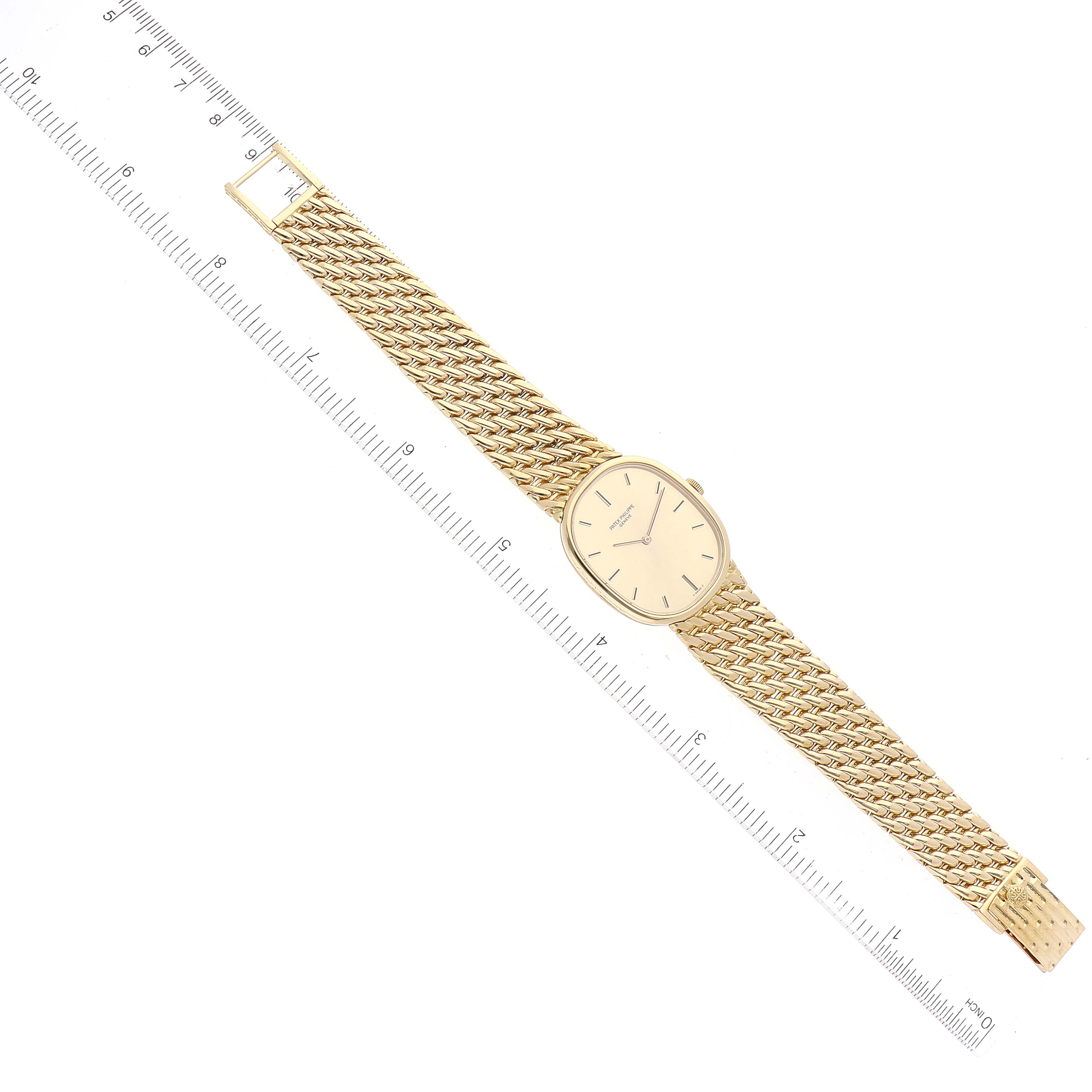 The image shows a top-down view of a Patek Philippe Golden Ellipse 3848/17 Men's Yellow Gold Champagne Dial 3848/17 Men's Yellow Gold Champagne Dial watch and a ruler for scale.