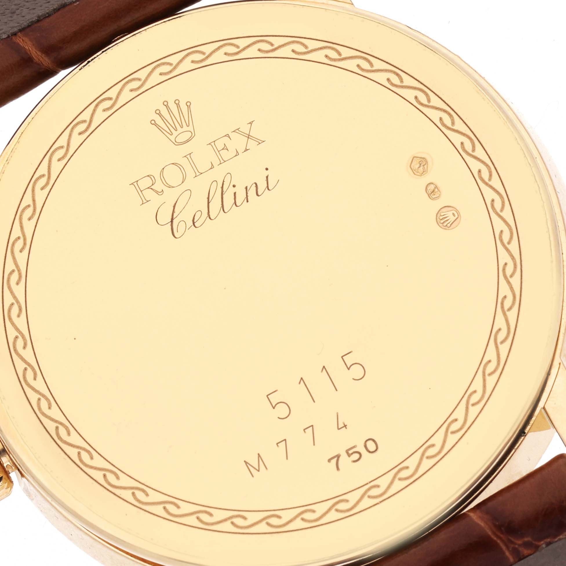 The image shows the back of a Rolex Cellini 5115 Men's Yellow Gold Champagne Dial 5115 Men's Yellow Gold Champagne Dial watch with engravings, including model and serial numbers, viewed from a close-up angle.