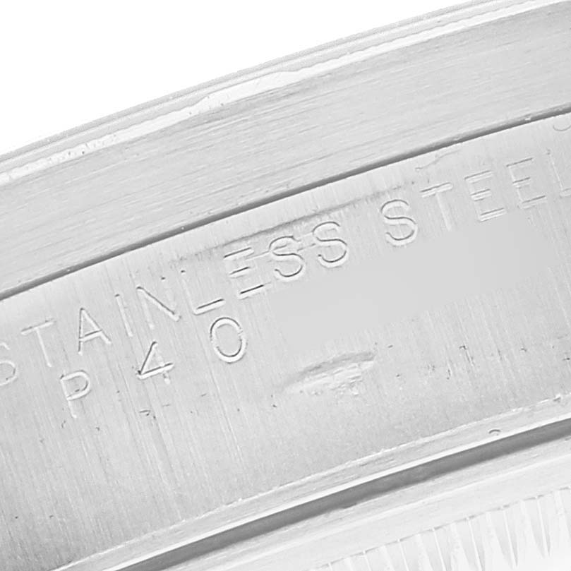 The image shows a close-up of the edge of a Rolex Date 15210 Men's Stainless Steel White Dial 15210 Men's Stainless Steel White Dial watch, highlighting "STAINLESS" engraved on the stainless steel part.