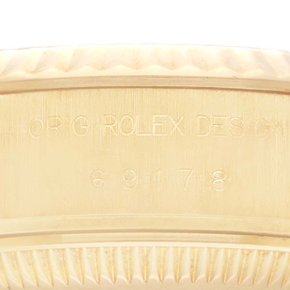 The image shows an up-close view of the side of a Rolex President 69178 Women's Yellow Gold Champagne Dial 69178 Women's Yellow Gold Champagne Dial model watch, highlighting the model and serial numbers engraved.