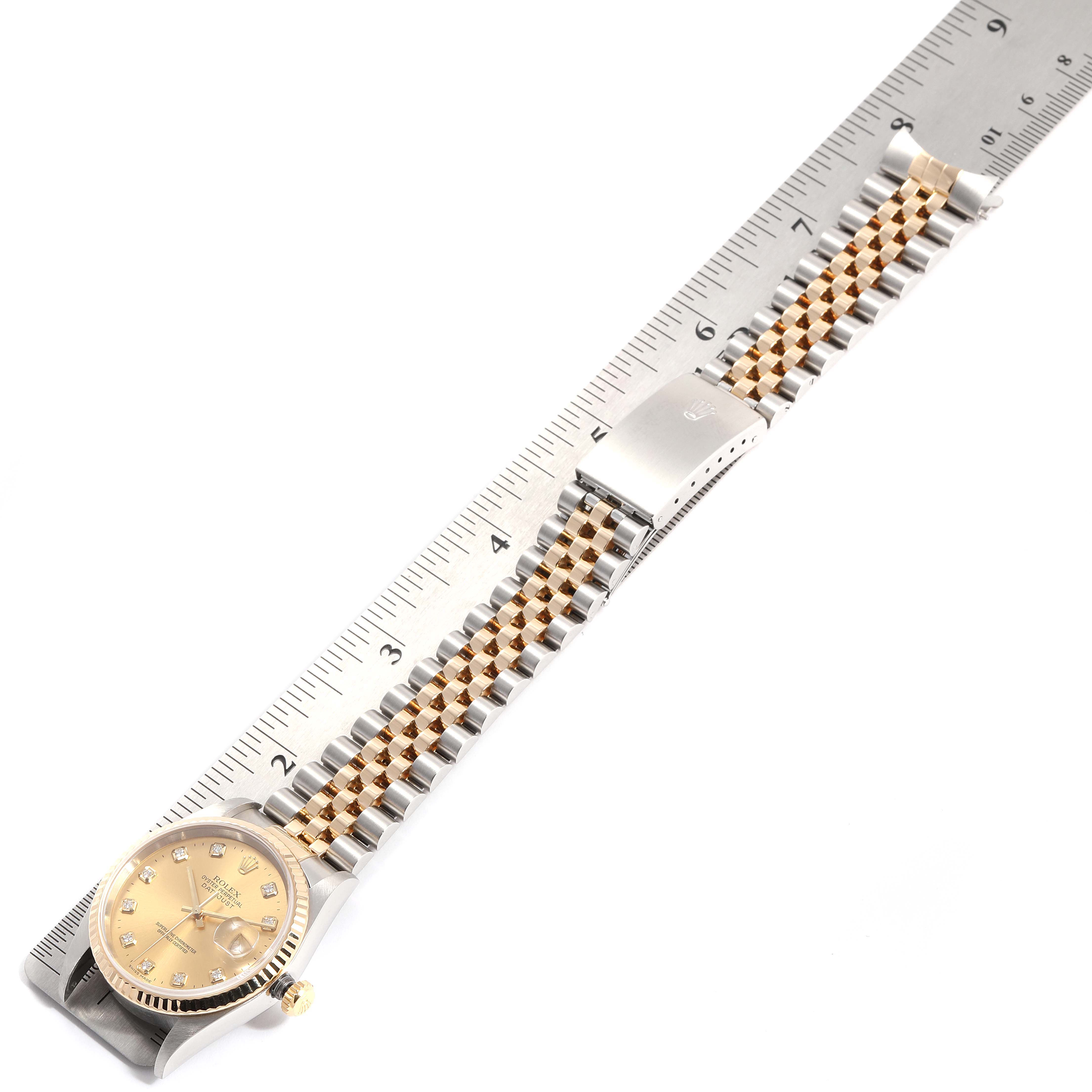 The image shows a Rolex Datejust 16233 Men
s Steel and Gold (two tone) Champagne Dial 16233 Men
s Steel and Gold (two tone) Champagne Dial watch laid flat next to a ruler, displaying the face, bracelet, and clasp.