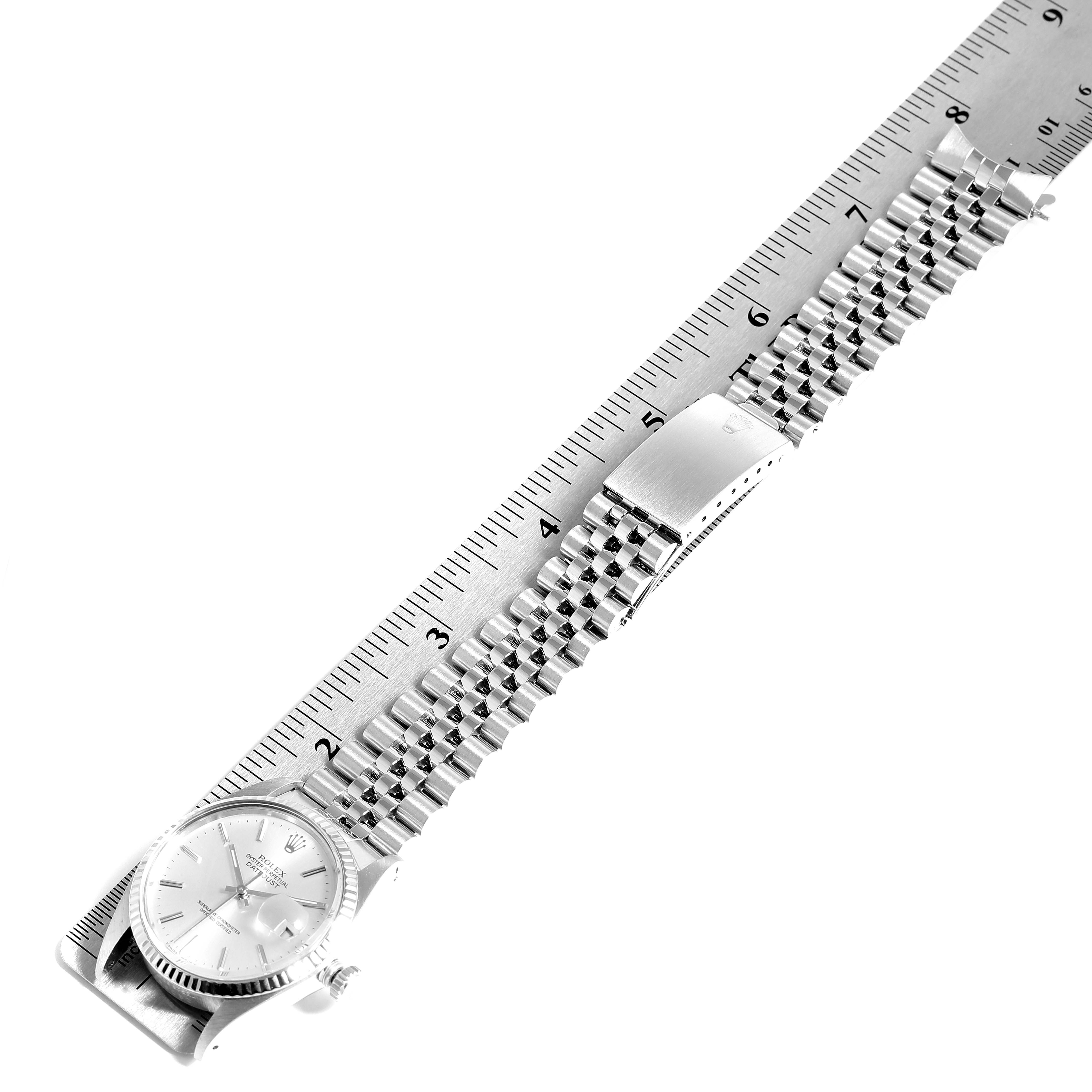 The image shows a top view of a Rolex Vintage Collection 16014 Men
s Stainless Steel Silver Dial 16014 Men
s Stainless Steel Silver Dial watch, with the face, bracelet, and clasp visible, alongside a ruler for scale.