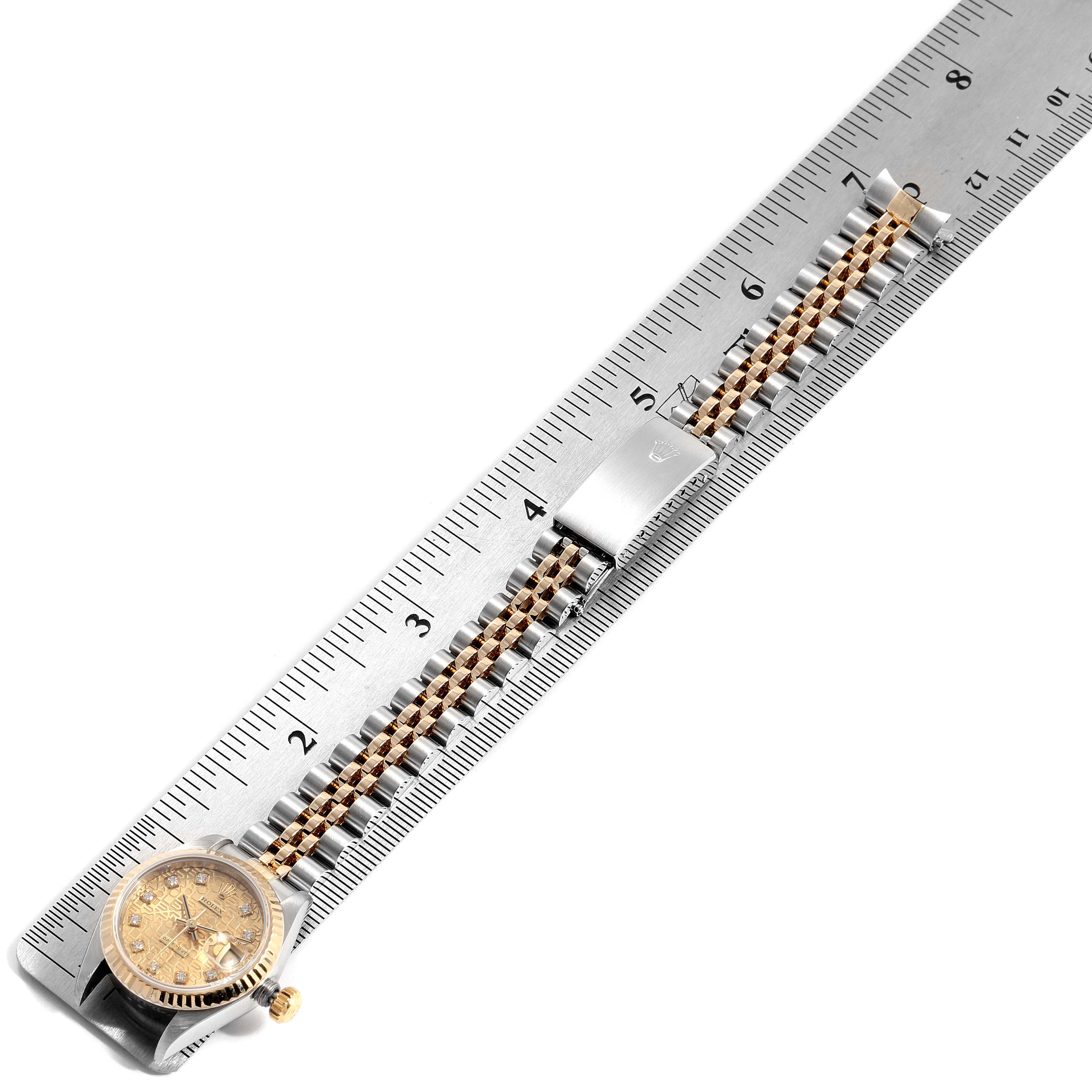 The image shows a top-down view of a Rolex Datejust 79173 Women
s Steel and Gold (two tone) Champagne Dial 79173 Women
s Steel and Gold (two tone) Champagne Dial watch with its gold and steel bracelet laid alongside a ruler.