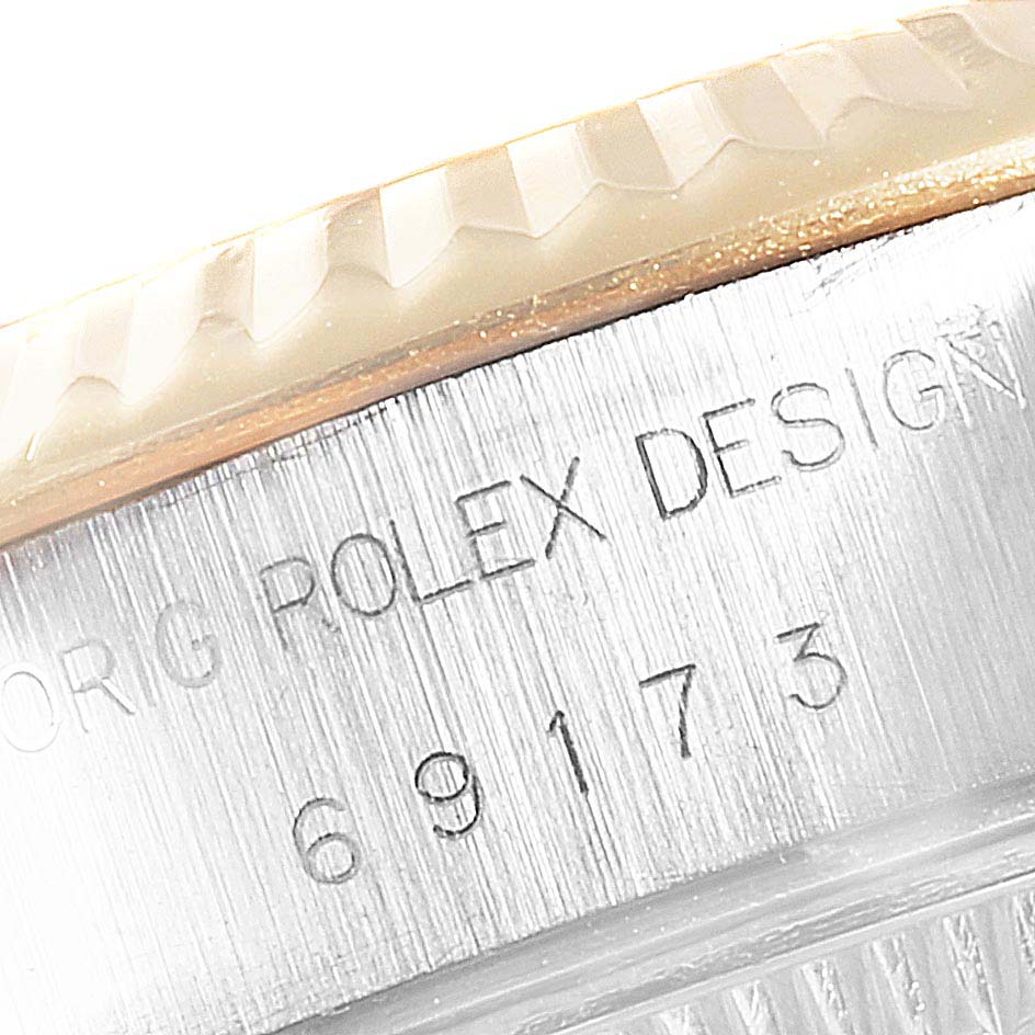 The image shows a close-up of the engraved case and bezel detail of a Rolex Datejust 69173 Women's Steel and Gold (two tone) Red Dial 69173 Women's Steel and Gold (two tone) Red Dial watch.