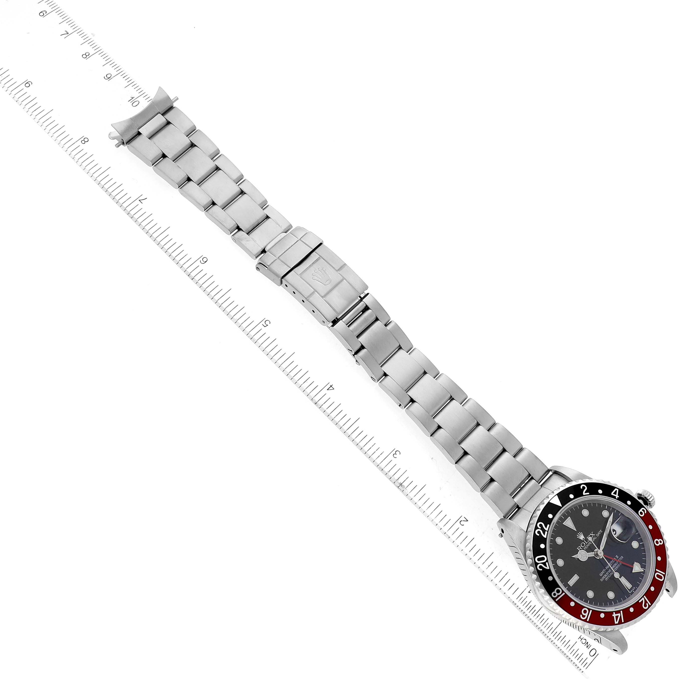 The image shows a top-down view of a Rolex GMT-Master 16710 Men
s Stainless Steel Black Dial 16710 Men
s Stainless Steel Black Dial watch with a metal bracelet next to a ruler for scale.
