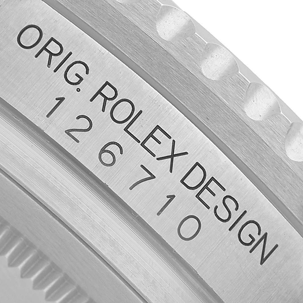 The image shows a close-up of the bezel and engraved serial number on a Rolex GMT-Master M126710GRNR Men's Stainless Steel Black Dial watch.