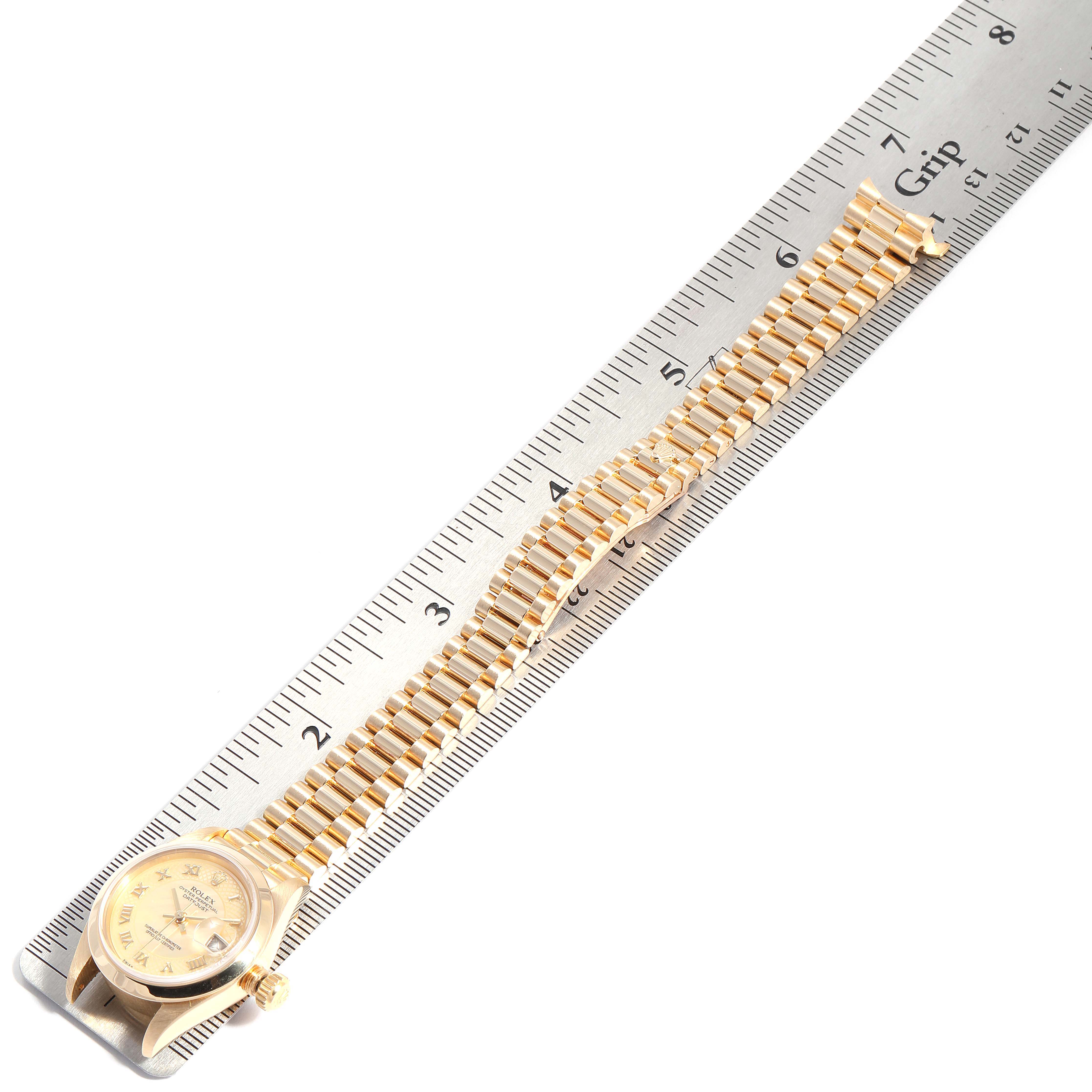 The image shows a Rolex President 79168 Women
s Yellow Gold Mother of Pearl Dial 79168 Women
s Yellow Gold Mother of Pearl Dial model watch, featuring its face, crown, and full bracelet, positioned next to a ruler for scale.