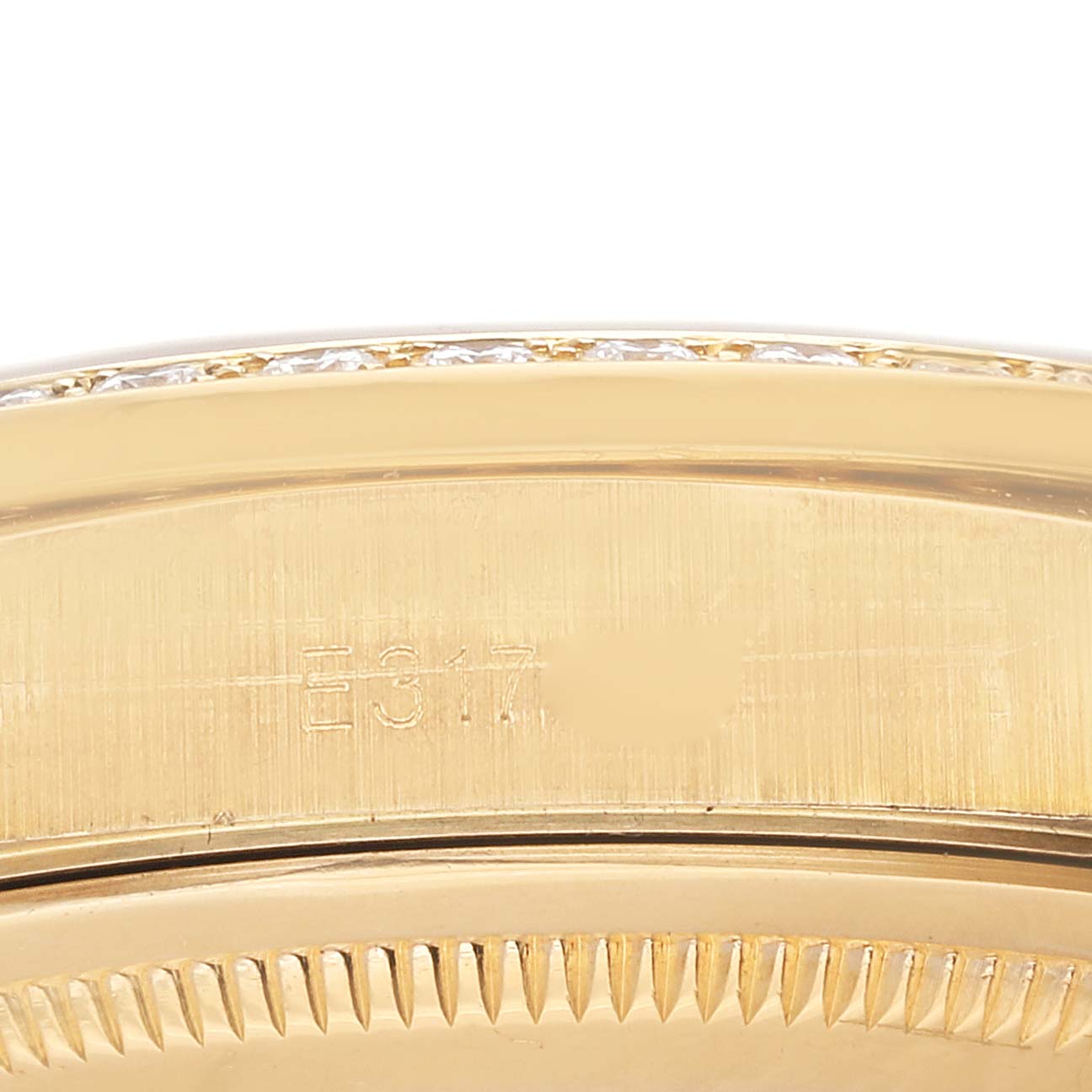 This image shows a close-up of the side of a Rolex President 18388 Men
s Yellow Gold Champagne Dial 18388 Men
s Yellow Gold Champagne Dial model watch, focusing on the bezel and some engraved serial numbers.