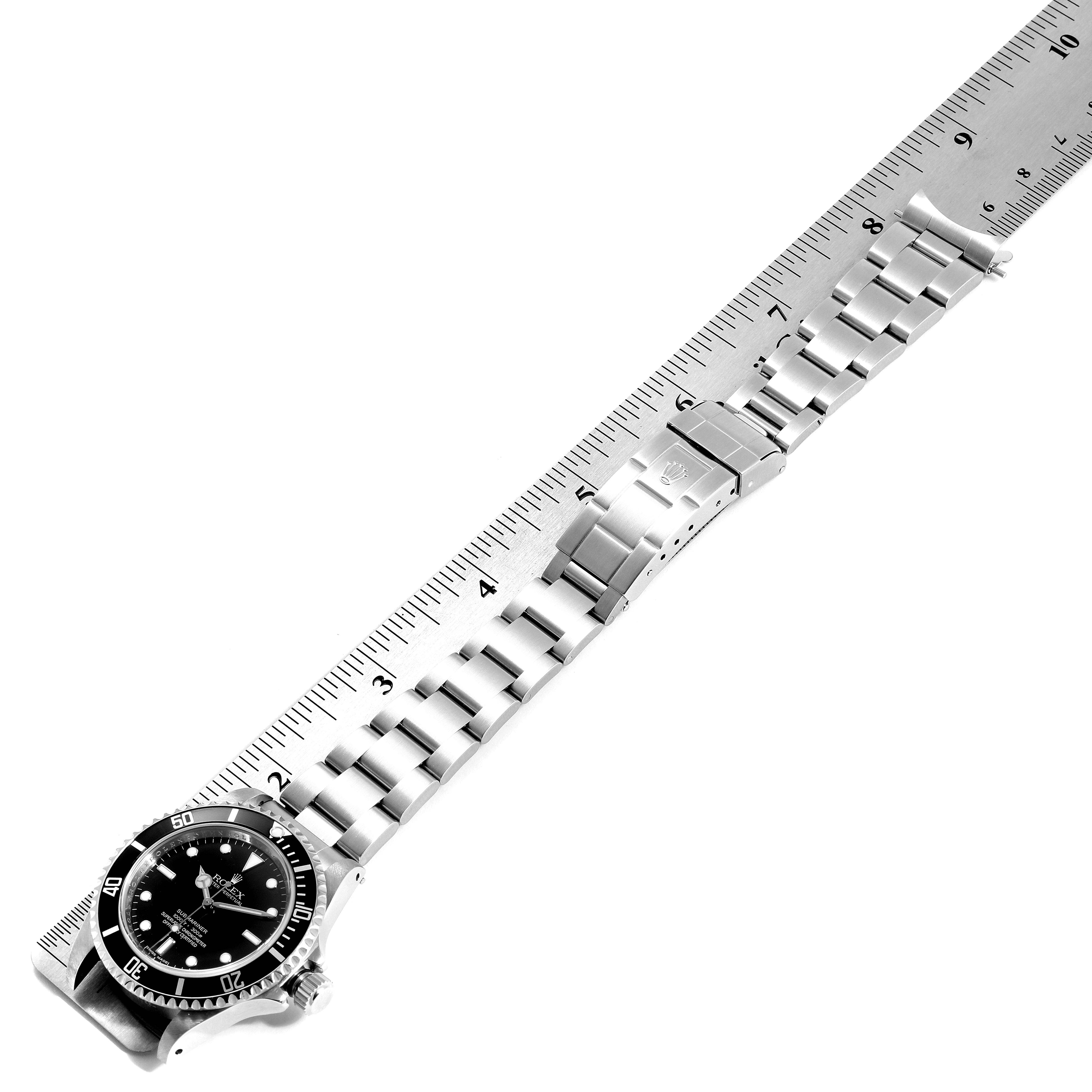 This image shows a Rolex Submariner 14060M Men
s Stainless Steel Black Dial 14060M Men
s Stainless Steel Black Dial watch laid flat against a ruler, displaying the face, bracelet, and clasp.