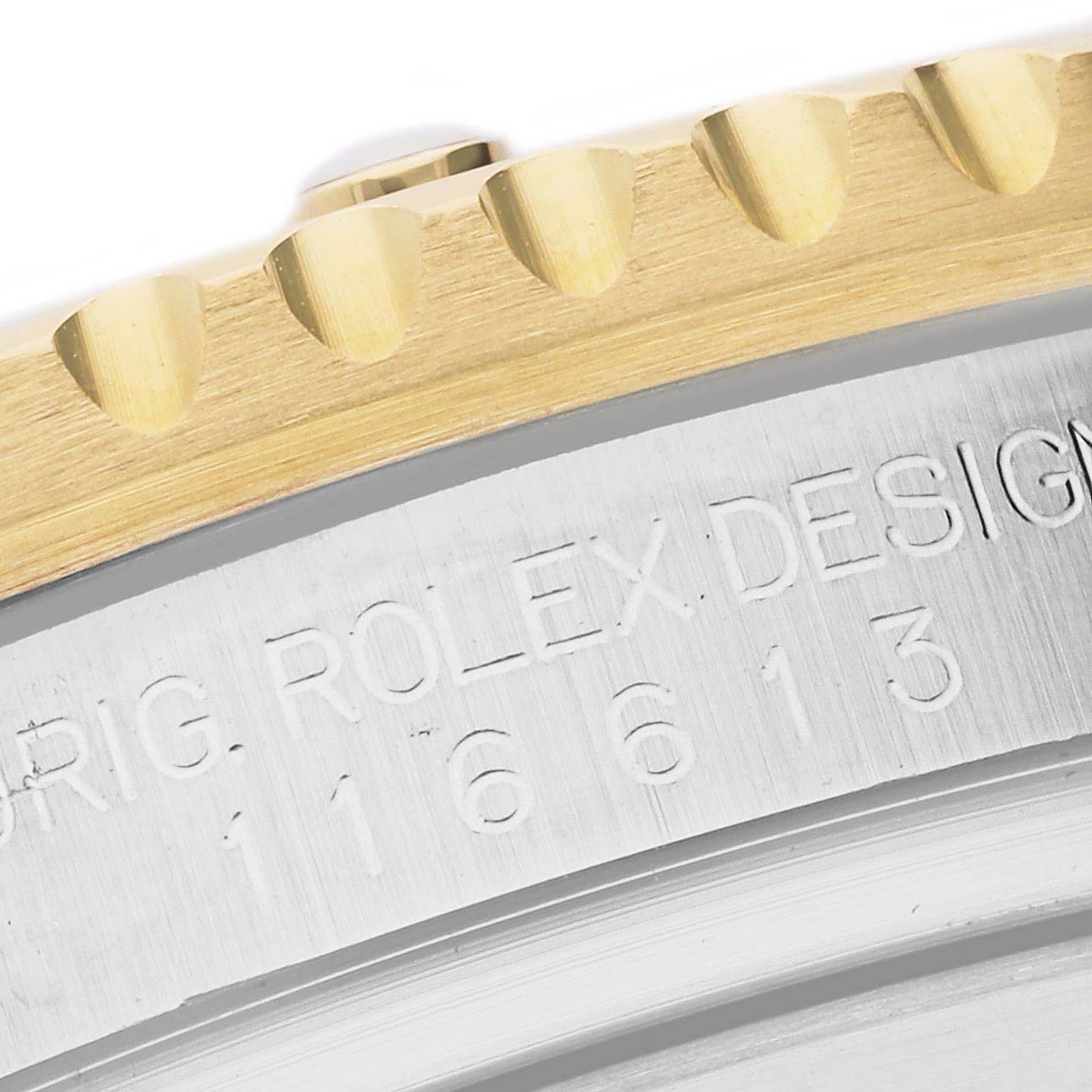 This close-up image shows the engraved text and part of the bezel teeth on a Rolex Submariner 116613LB Men's Steel and Gold (two tone) Blue Dial 116613LB Men's Steel and Gold (two tone) Blue Dial watch.