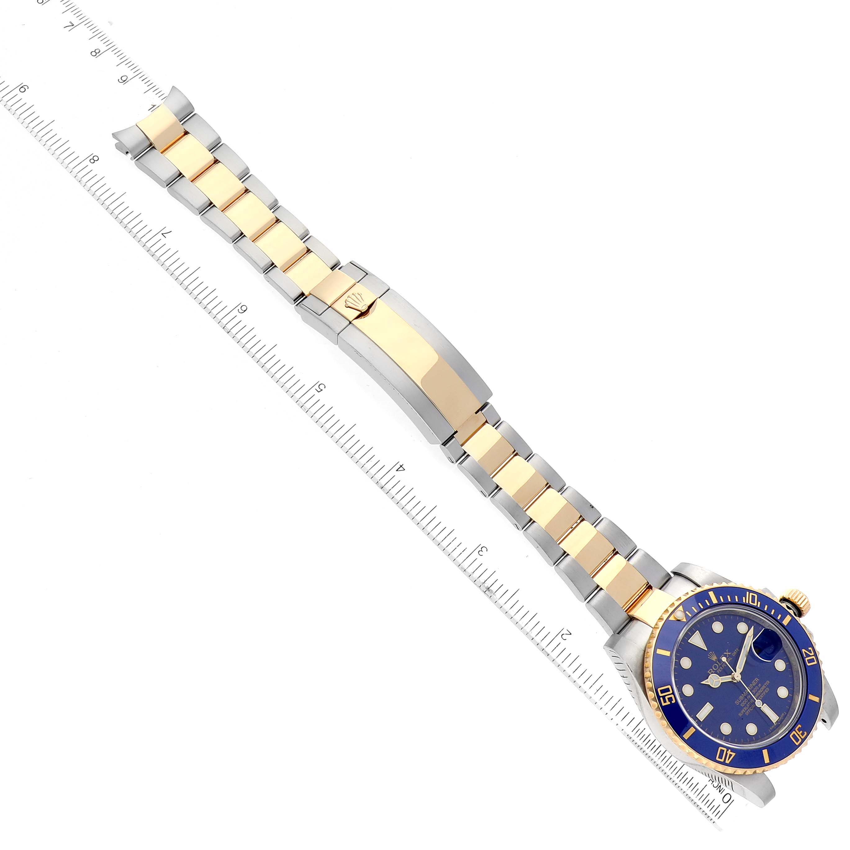 The image shows a side angle of a Rolex Submariner 116613LB Men's Steel and Gold (two tone) Blue Dial 116613LB Men's Steel and Gold (two tone) Blue Dial watch, displaying its bracelet, clasp, and dial alongside a ruler for scale.