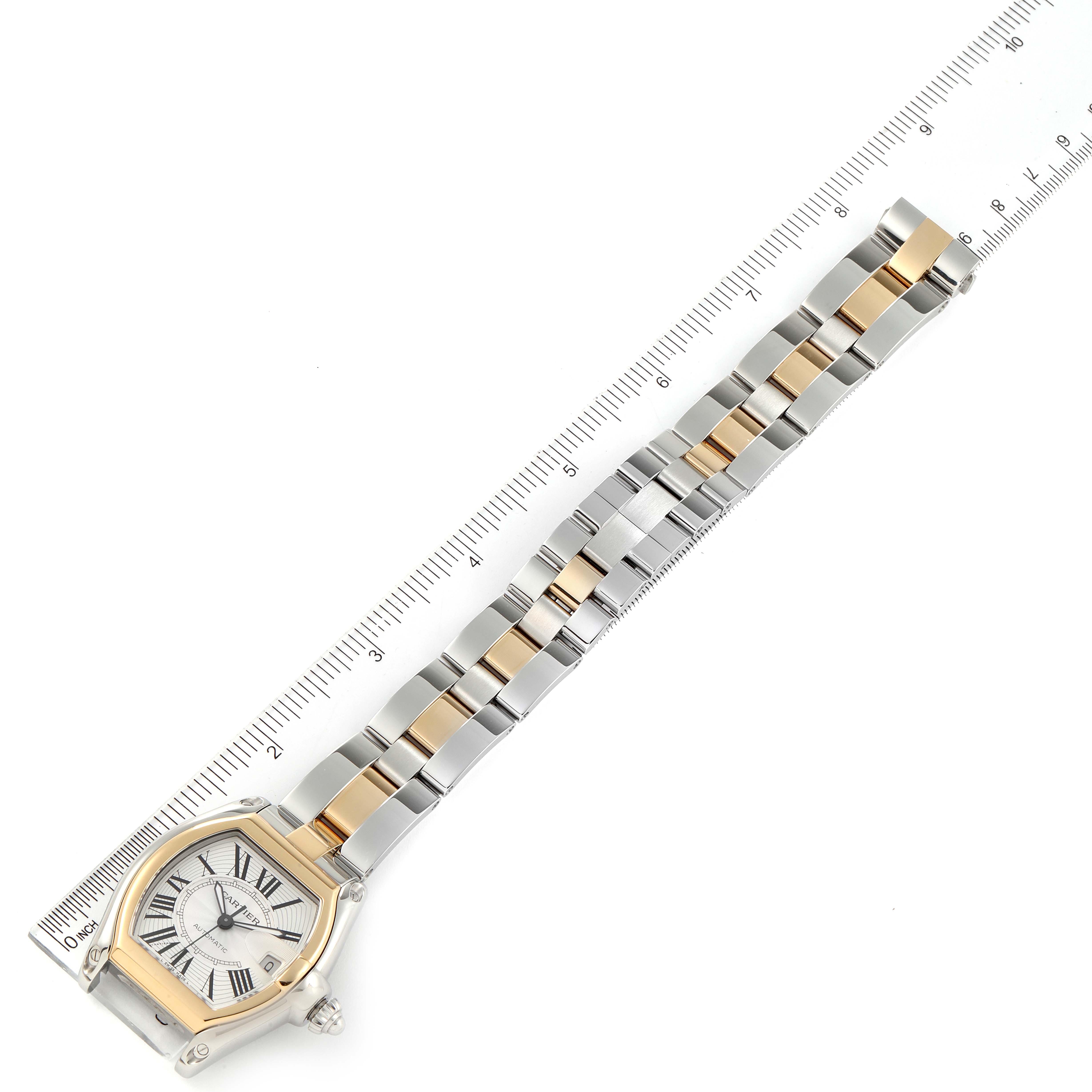 The Cartier Roadster W62031Y4 Men's Steel and Gold (two tone) Silver Dial W62031Y4 Men's Steel and Gold (two tone) Silver Dial watch is shown from an angled overhead view, displaying its face and full bracelet alongside a ruler.