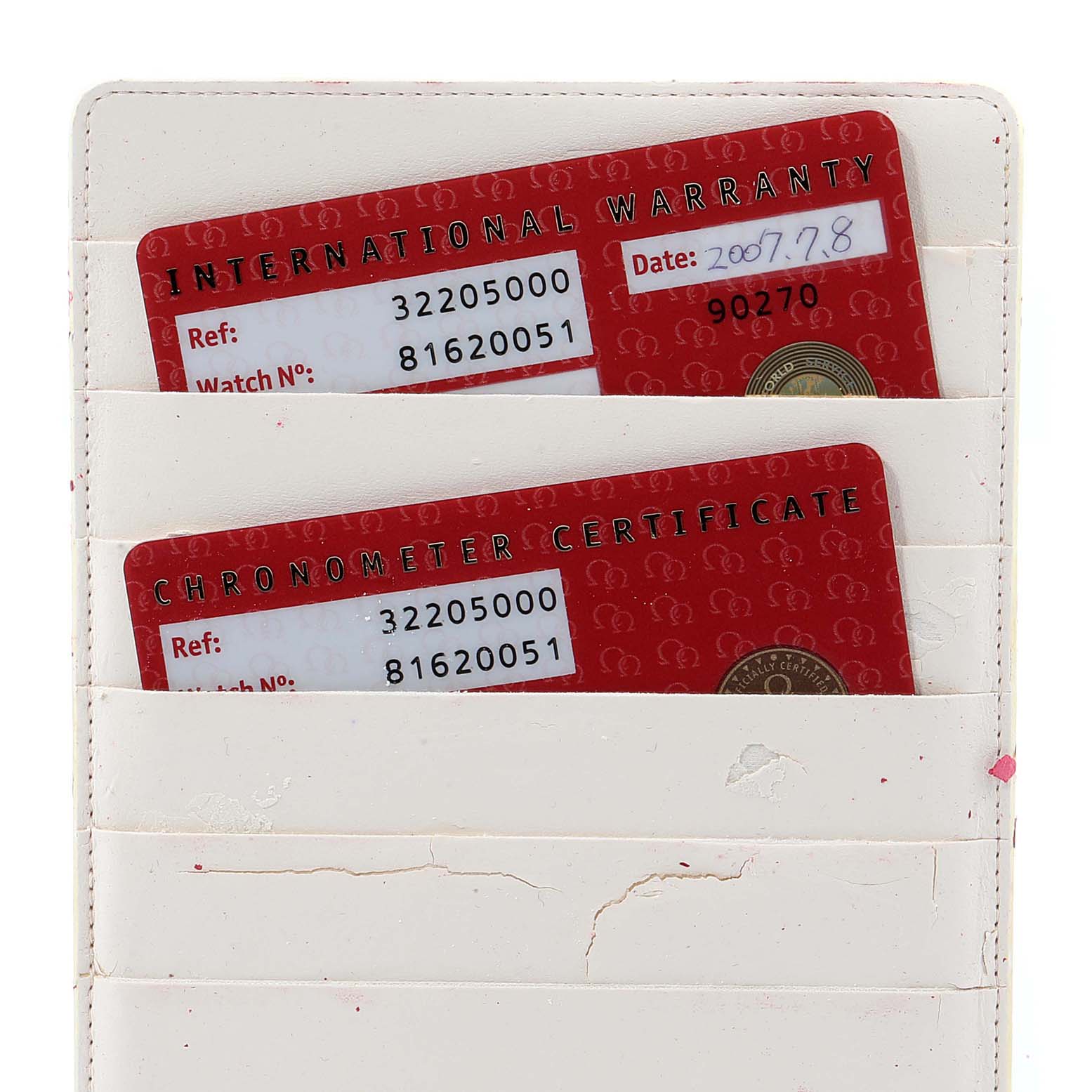 The image shows a partial view of a white cardholder containing Omega Speedmaster 3220.50.00 Men
s Stainless Steel Black Dial 3220.50.00 Men
s Stainless Steel Black Dial International Warranty and Chronometer Certificate cards.