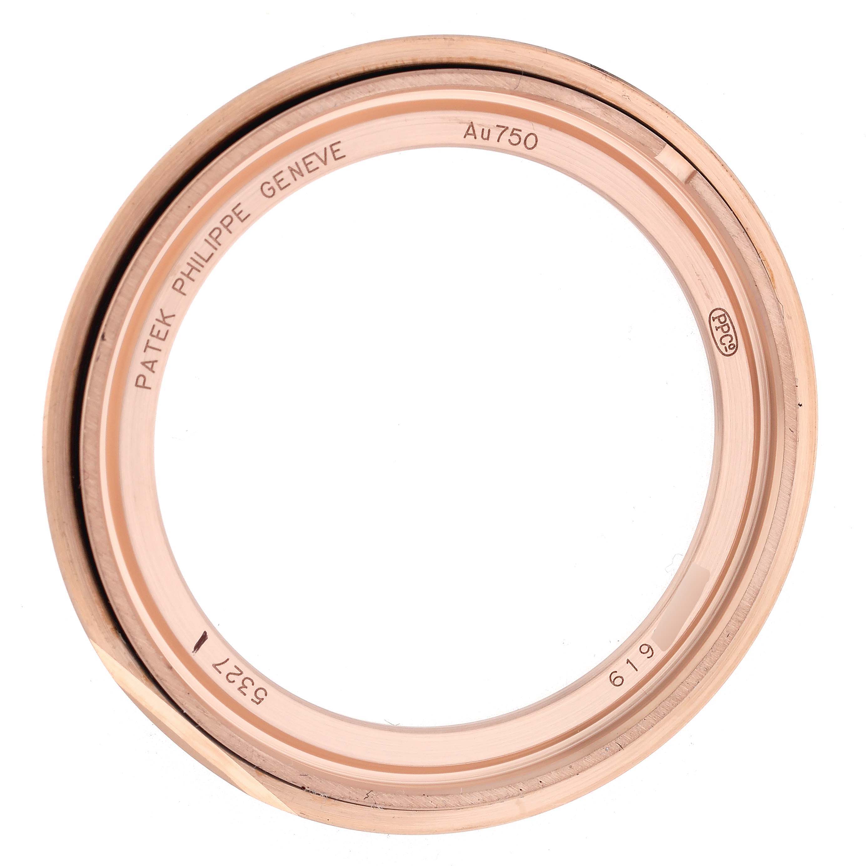 The image shows the bezel of a Patek Philippe Complications 5327R Men
s Rose Gold White Dial 5327R Men
s Rose Gold White Dial model, highlighting engravings and gold markings from a top view.