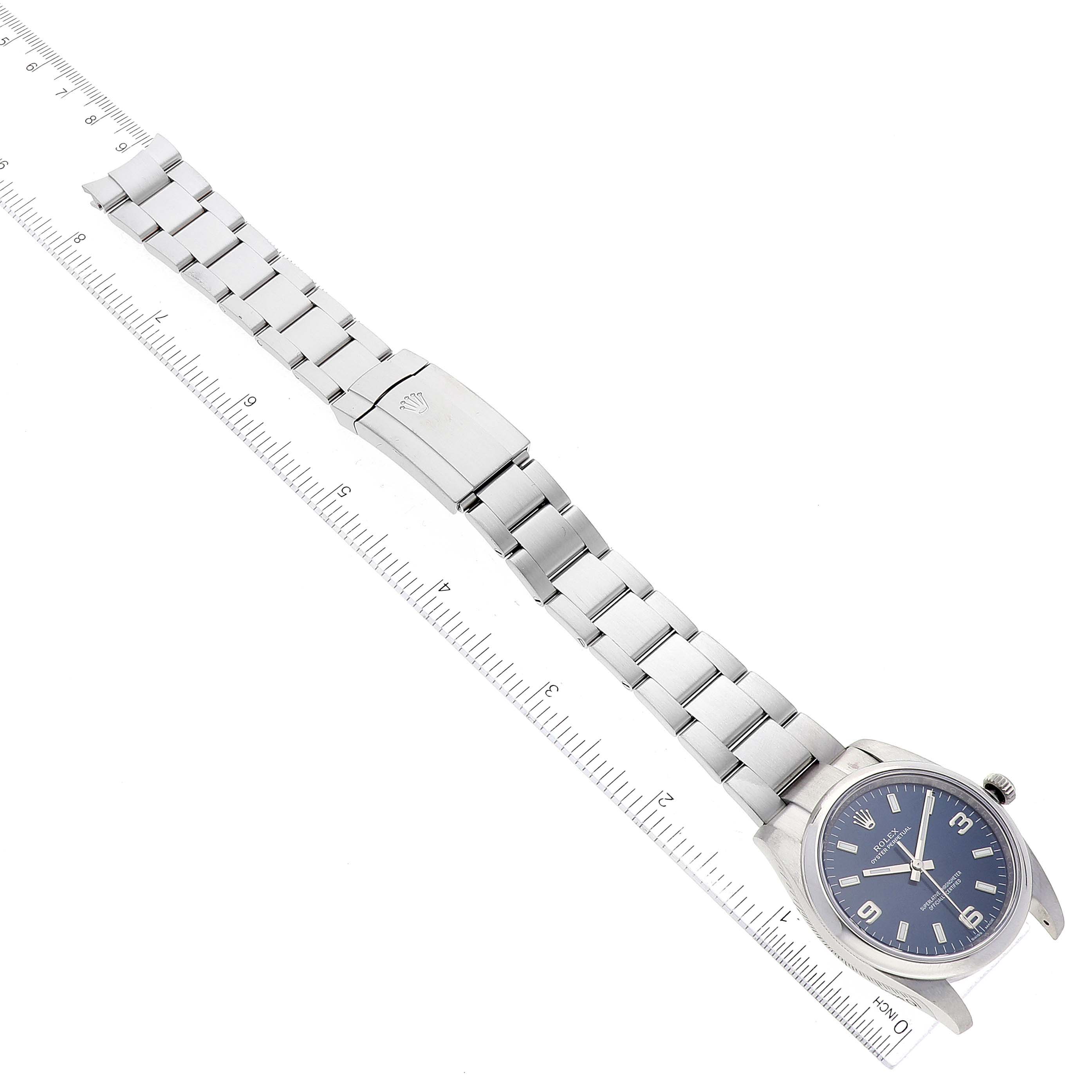 The image shows a top-down view of a Rolex Oyster Perpetual 114200 Men's Stainless Steel Blue Dial 114200 Men's Stainless Steel Blue Dial watch, highlighting the bracelet and clasp alongside a ruler for measurement.