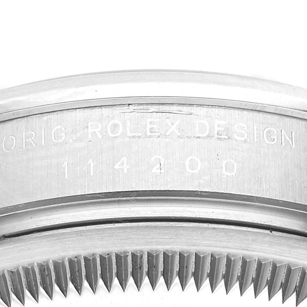 This image shows a close-up of the casing and bezel edge of a Rolex Oyster Perpetual 114200 Men's Stainless Steel Blue Dial 114200 Men's Stainless Steel Blue Dial watch.