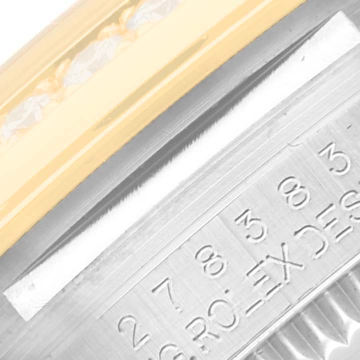 This image shows a close-up view of the edge of a Mid-Size Rolex watch, including part of the bezel and engraved inner case.