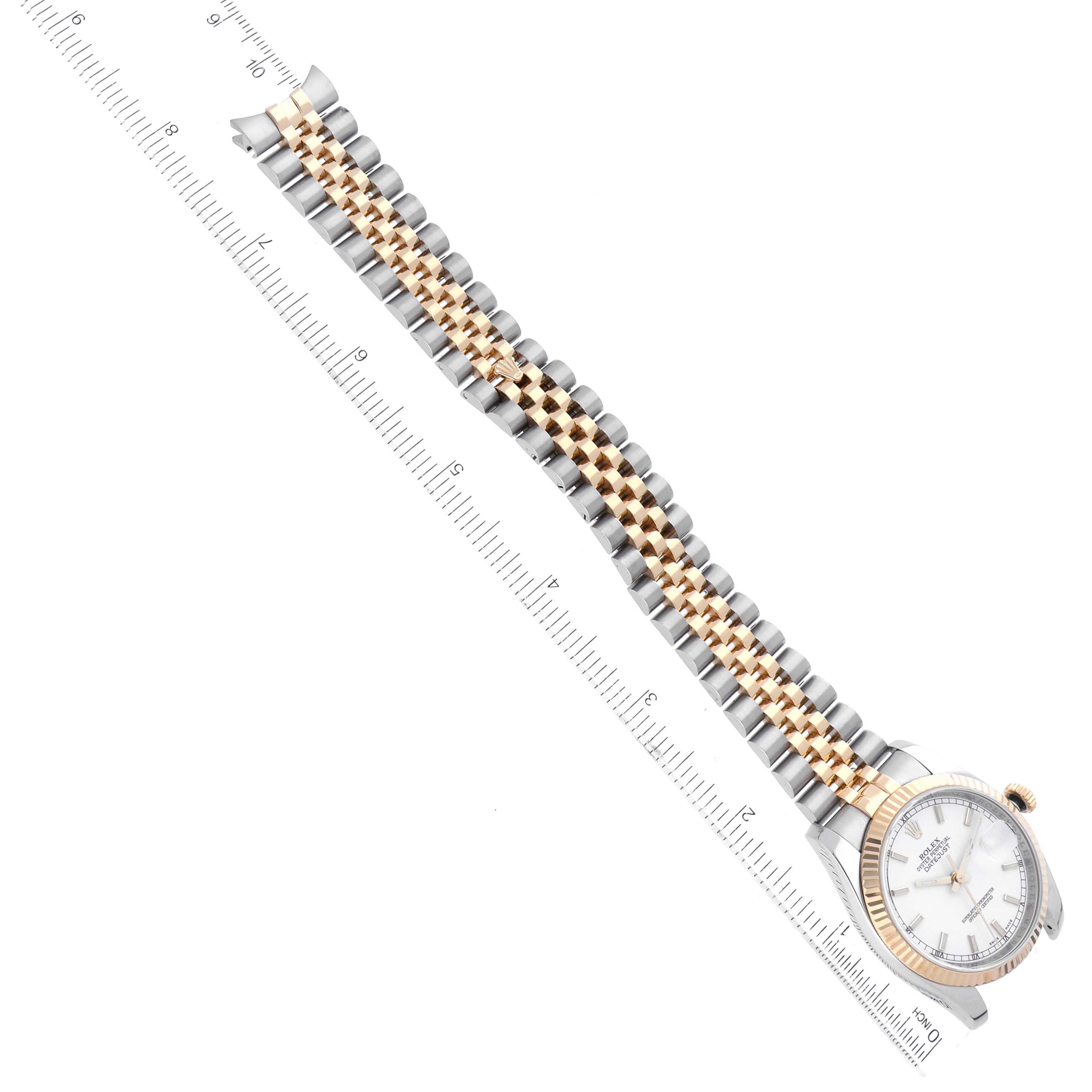 This image shows the Rolex Datejust 116233 Men's Steel and Gold (two tone) White Dial 116233 Men's Steel and Gold (two tone) White Dial watch at an angle, featuring its face, bezel, and bracelet with a measuring ruler.