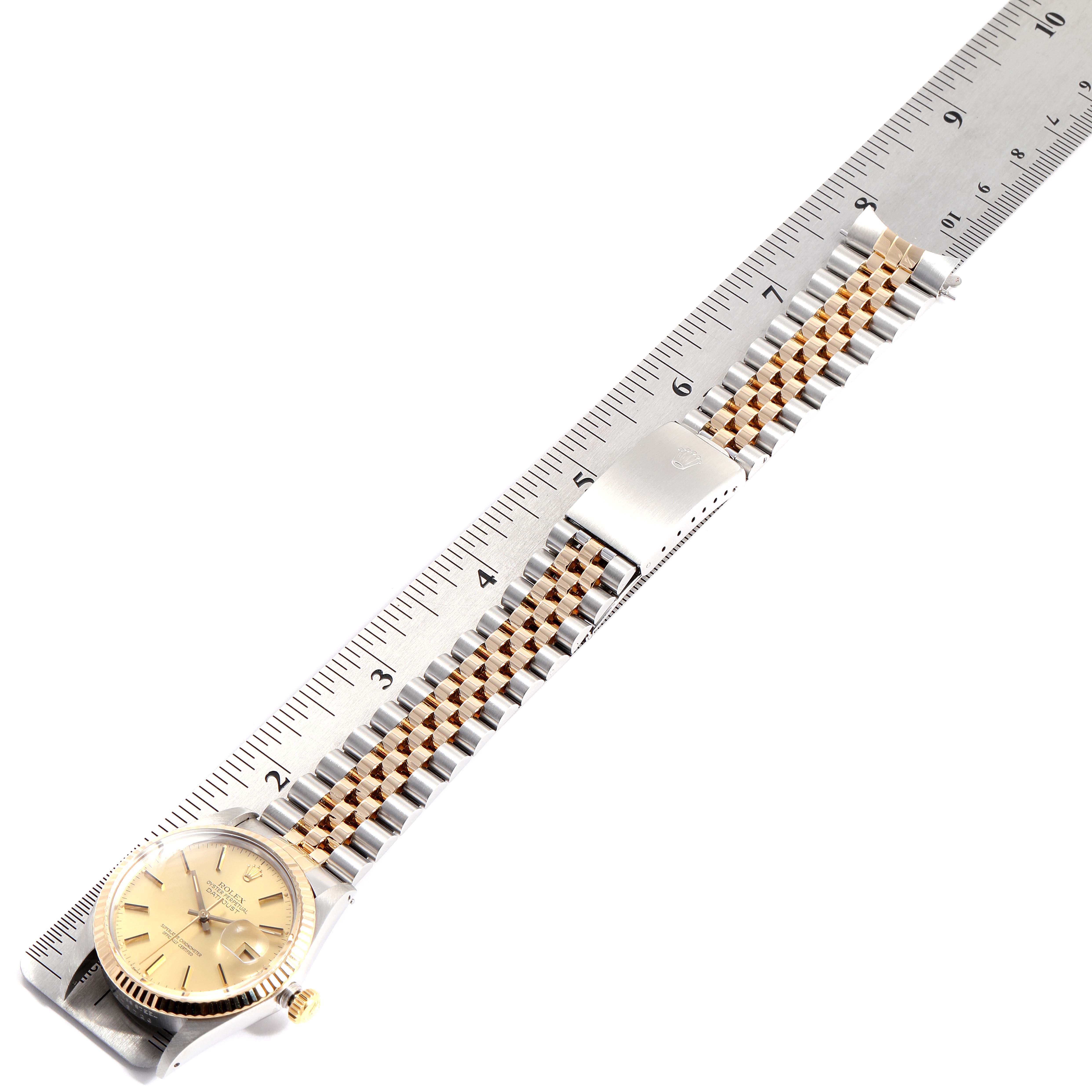 The image shows a Rolex Datejust 16013 Men
s Steel and Gold (two tone) Champagne Dial 16013 Men
s Steel and Gold (two tone) Champagne Dial watch laid flat next to a ruler, displaying the dial, bracelet, and clasp.