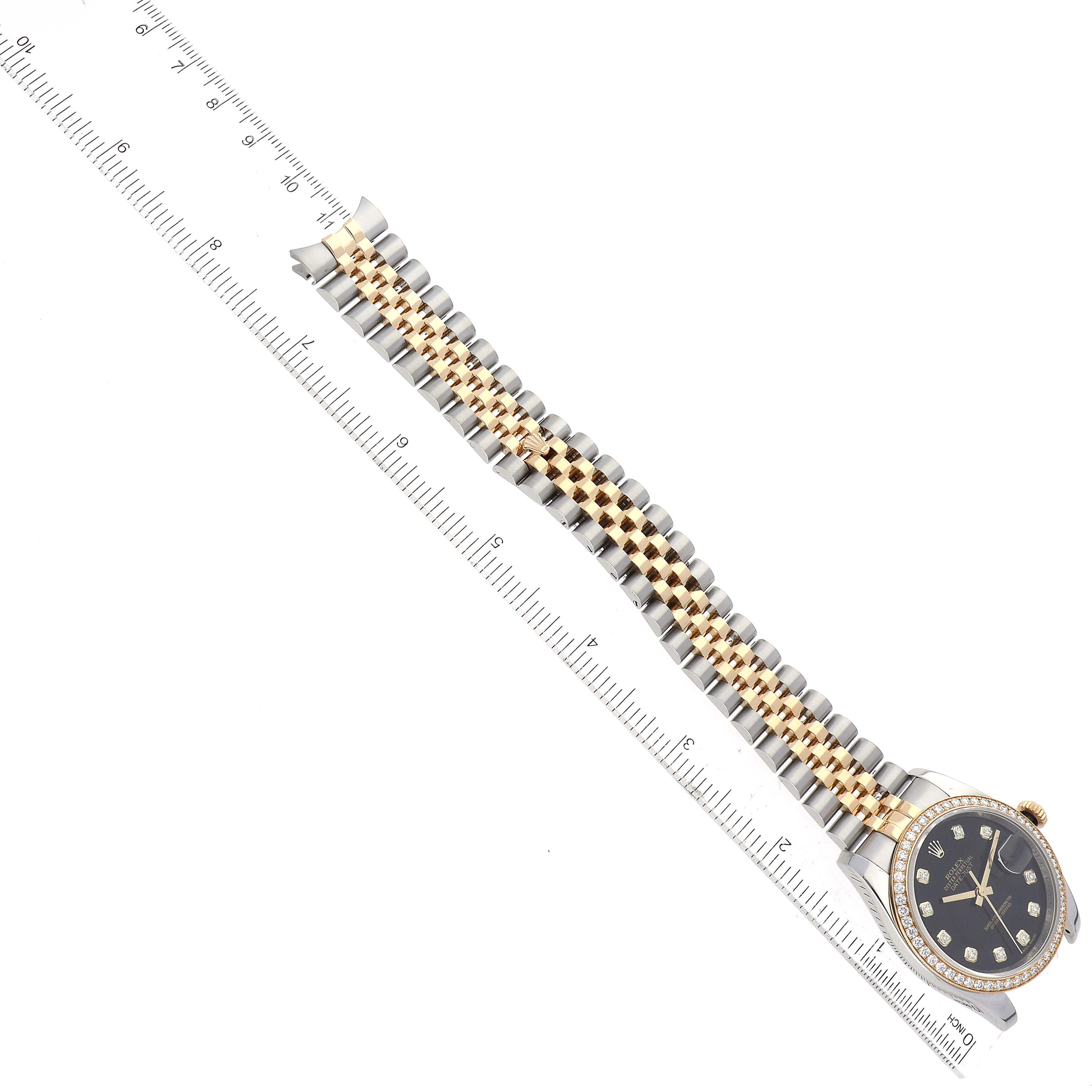 The image shows a top-down view of a Rolex Datejust 116243 Men's Steel and Gold (two tone) Black Dial 116243 Men's Steel and Gold (two tone) Black Dial watch, with the black dial, diamond bezel, and two-tone bracelet visible alongside a measuring ruler.