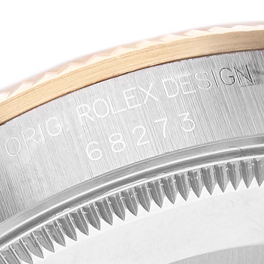 This close-up image of a Rolex Mid-Size 68273 Women
s Steel and Gold (two tone) Champagne Dial 68273 Women
s Steel and Gold (two tone) Champagne Dial model shows part of the bezel and case with engraved text "ORIG. ROLEX DESIGN 68273."