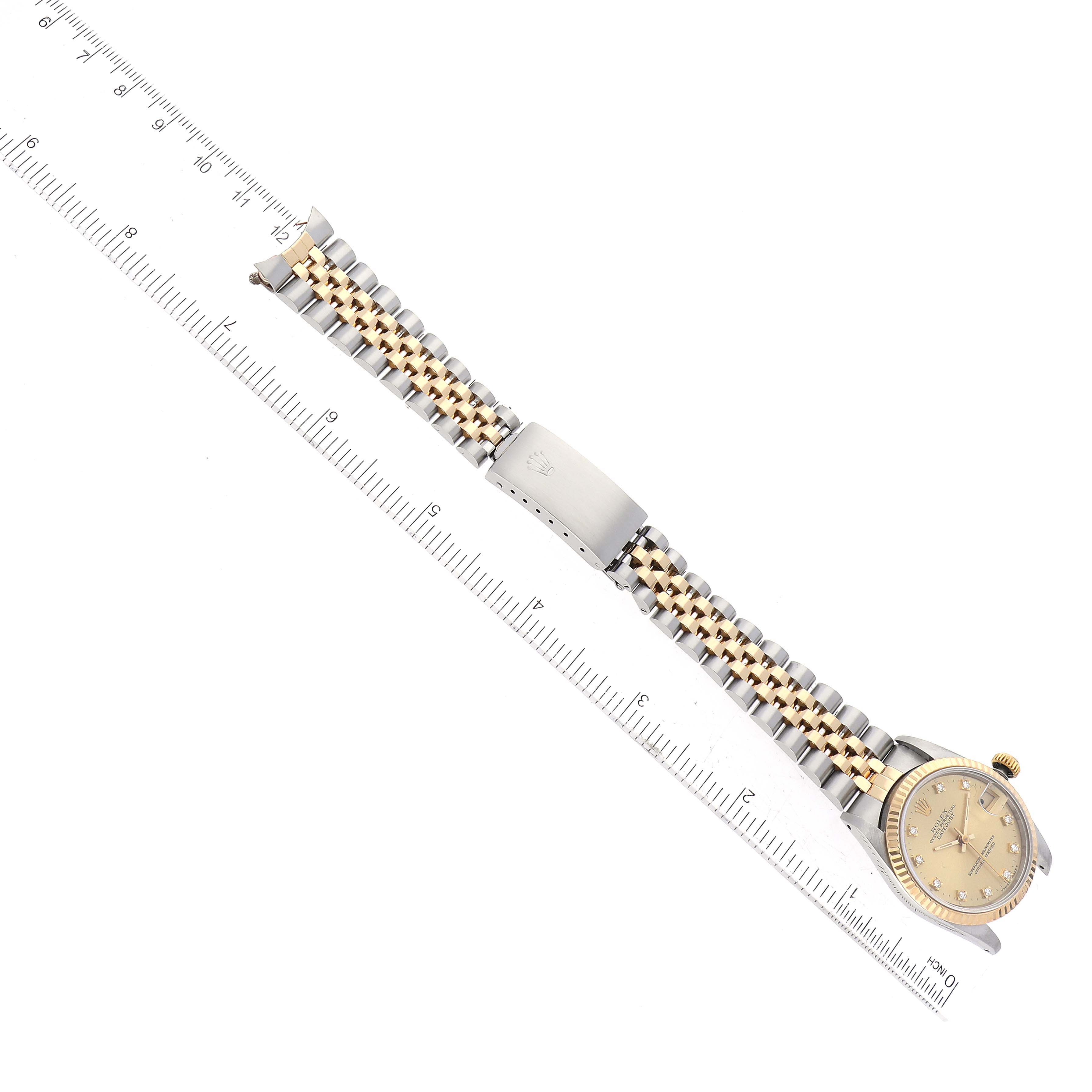 The Rolex Mid-Size 68273 Women's Steel and Gold (two tone) Champagne Dial 68273 Women's Steel and Gold (two tone) Champagne Dial model watch is shown from a top view, displaying the face, bracelet, and clasp next to a ruler.