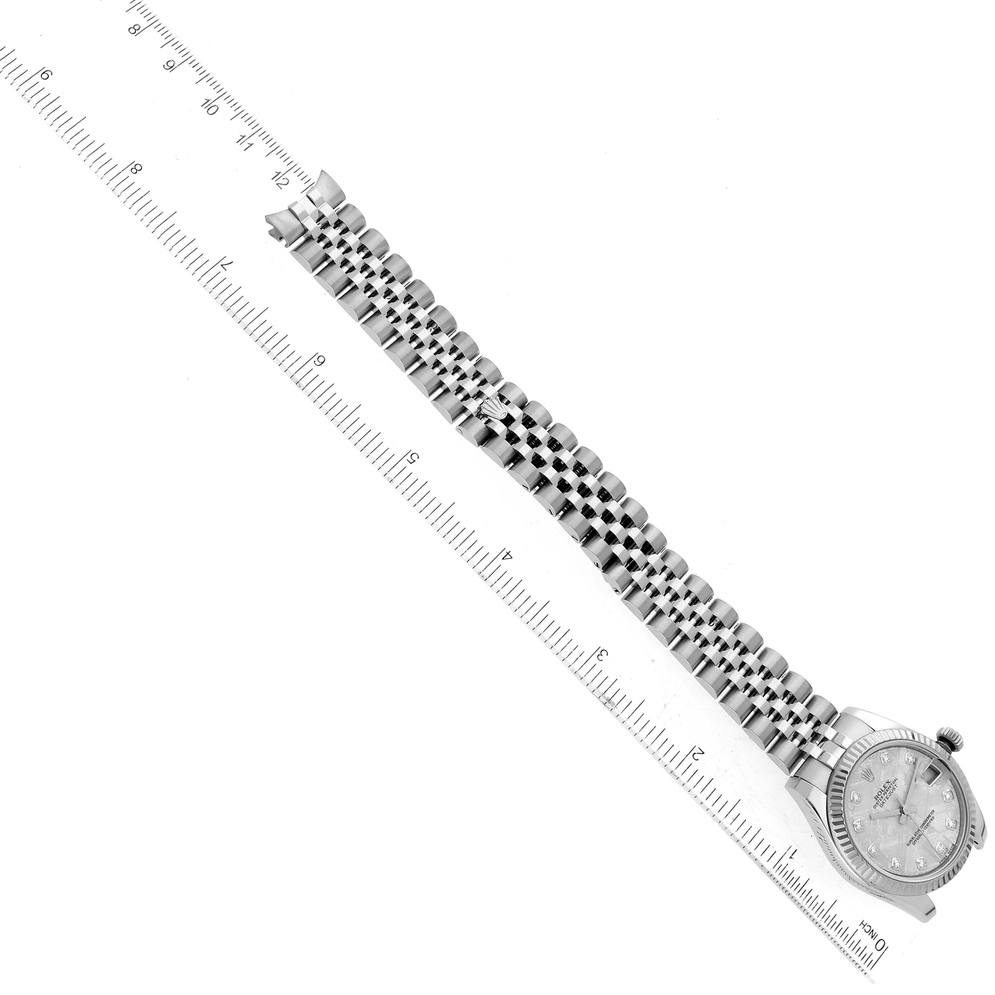 The image shows a diagonal top-down view of a Mid-Size Rolex watch with a stainless steel bracelet and a ruler for scale.