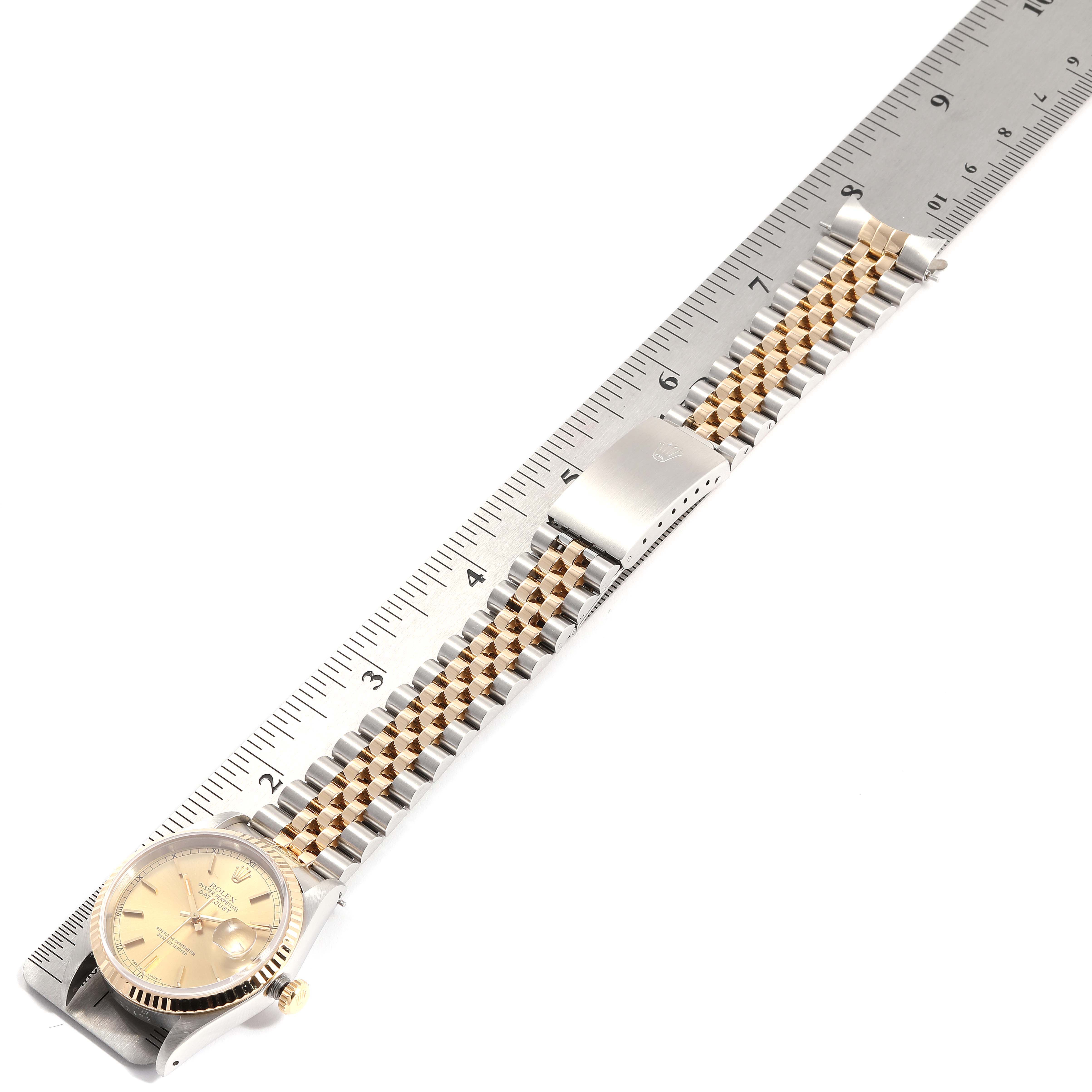 The image shows a Rolex Datejust 16233 Men's Steel and Gold (two tone) Champagne Dial 16233 Men's Steel and Gold (two tone) Champagne Dial watch laid flat next to a ruler, highlighting the dial, bracelet, and clasp.