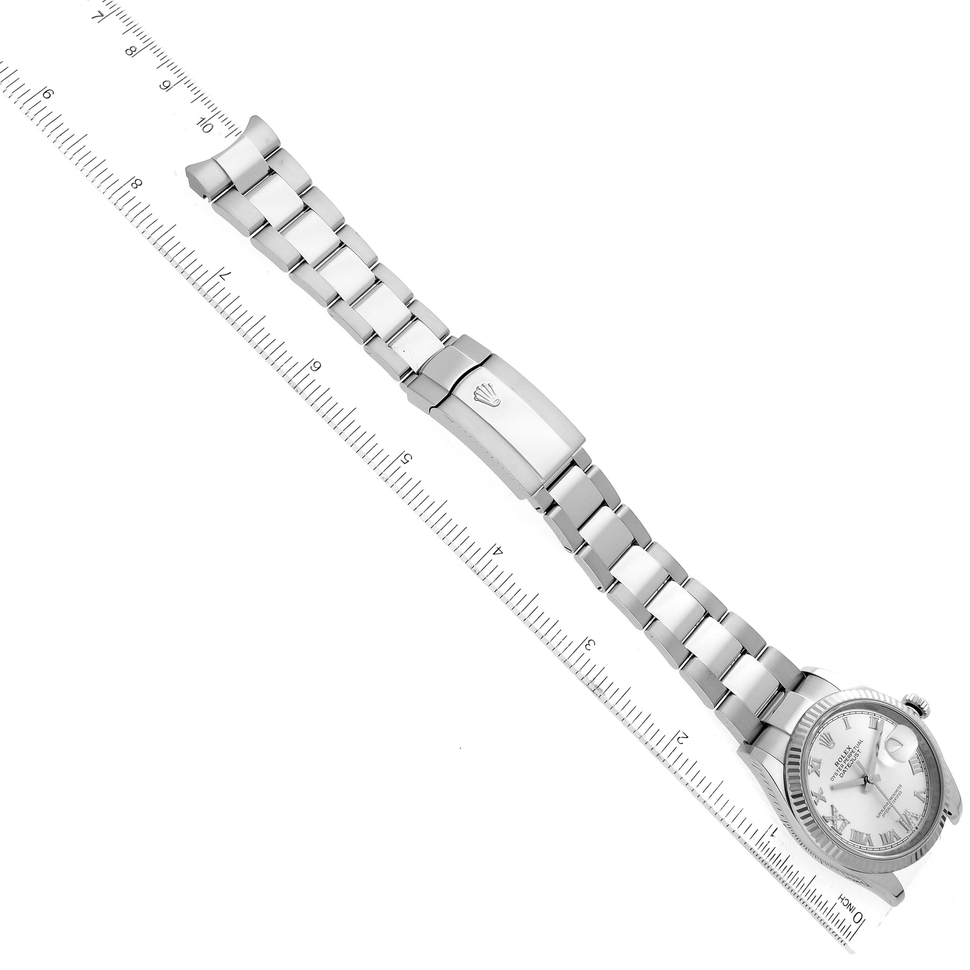The Rolex Datejust 126234 Men's Stainless Steel Silver Dial 126234 Men's Stainless Steel Silver Dial watch is shown from an overhead angle, displaying the face, bracelet, and deployment clasp, alongside a measuring ruler.