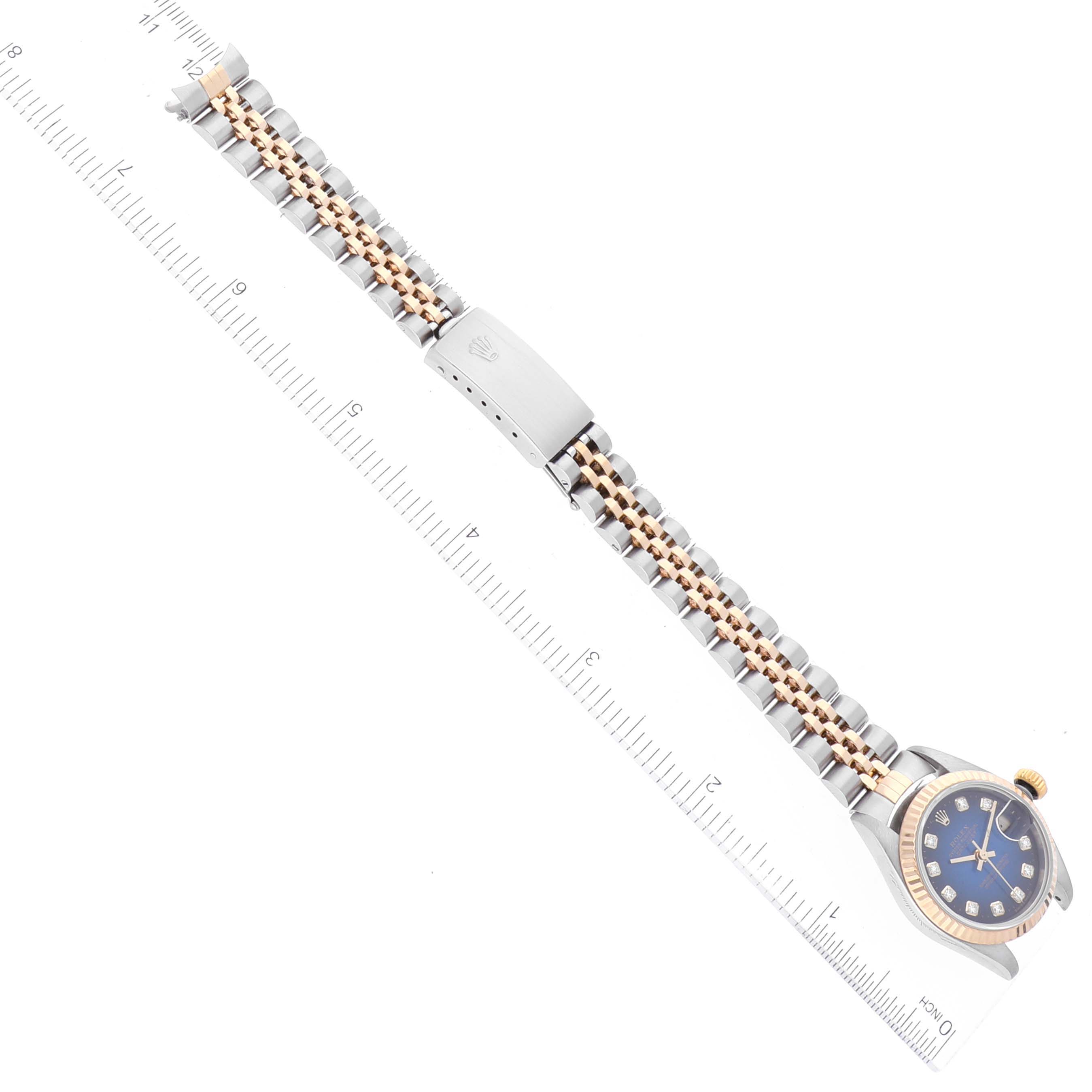This image shows a Rolex Datejust 79173 Women's Steel and Gold (two tone) Blue Dial 79173 Women's Steel and Gold (two tone) Blue Dial watch with a blue dial, gold bezel, and two-tone bracelet, laid flat along a ruler.