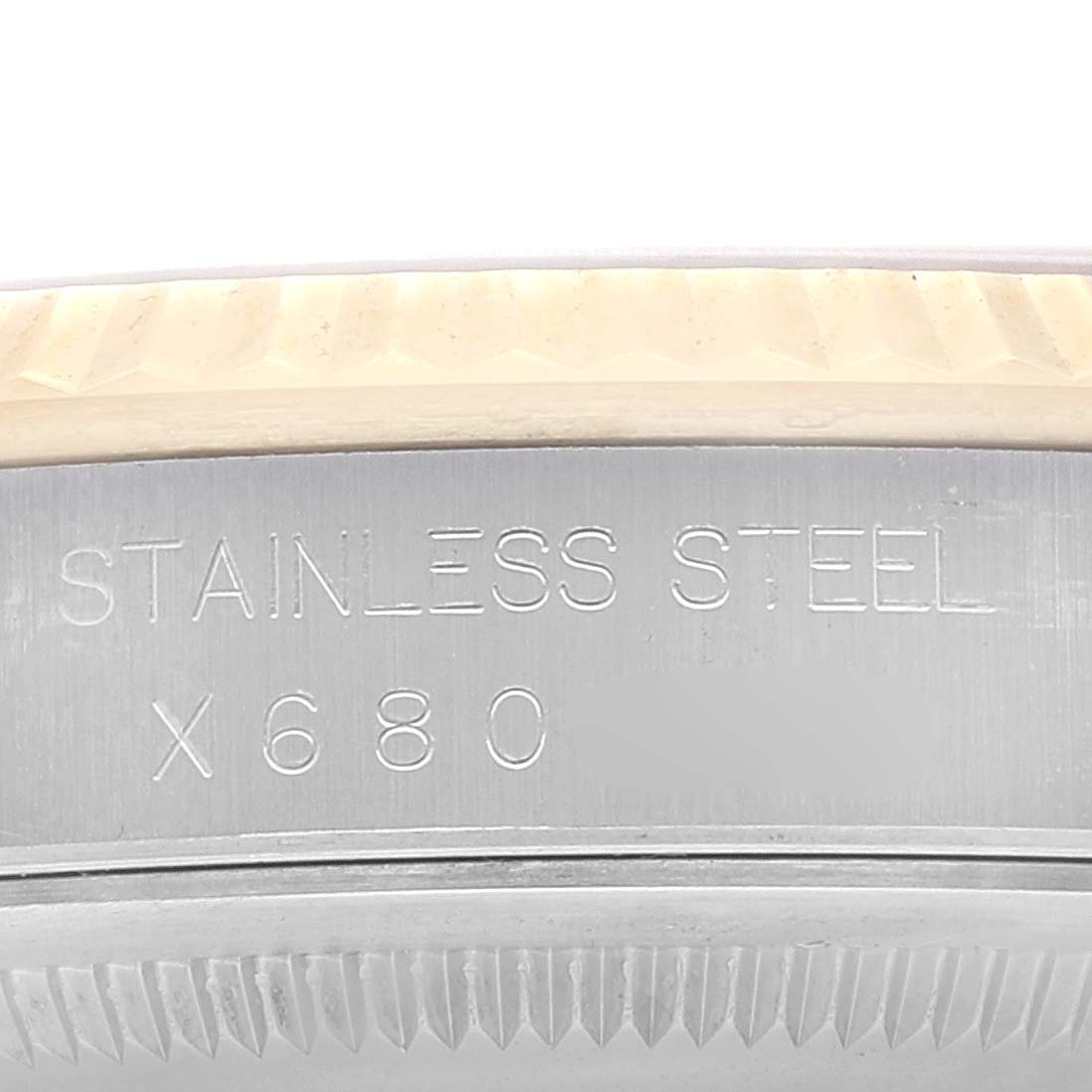 This close-up image of a Rolex Datejust 16233 Men's Steel and Gold (two tone) Champagne Dial 16233 Men's Steel and Gold (two tone) Champagne Dial model shows the stainless steel case with engravings and part of the fluted bezel.