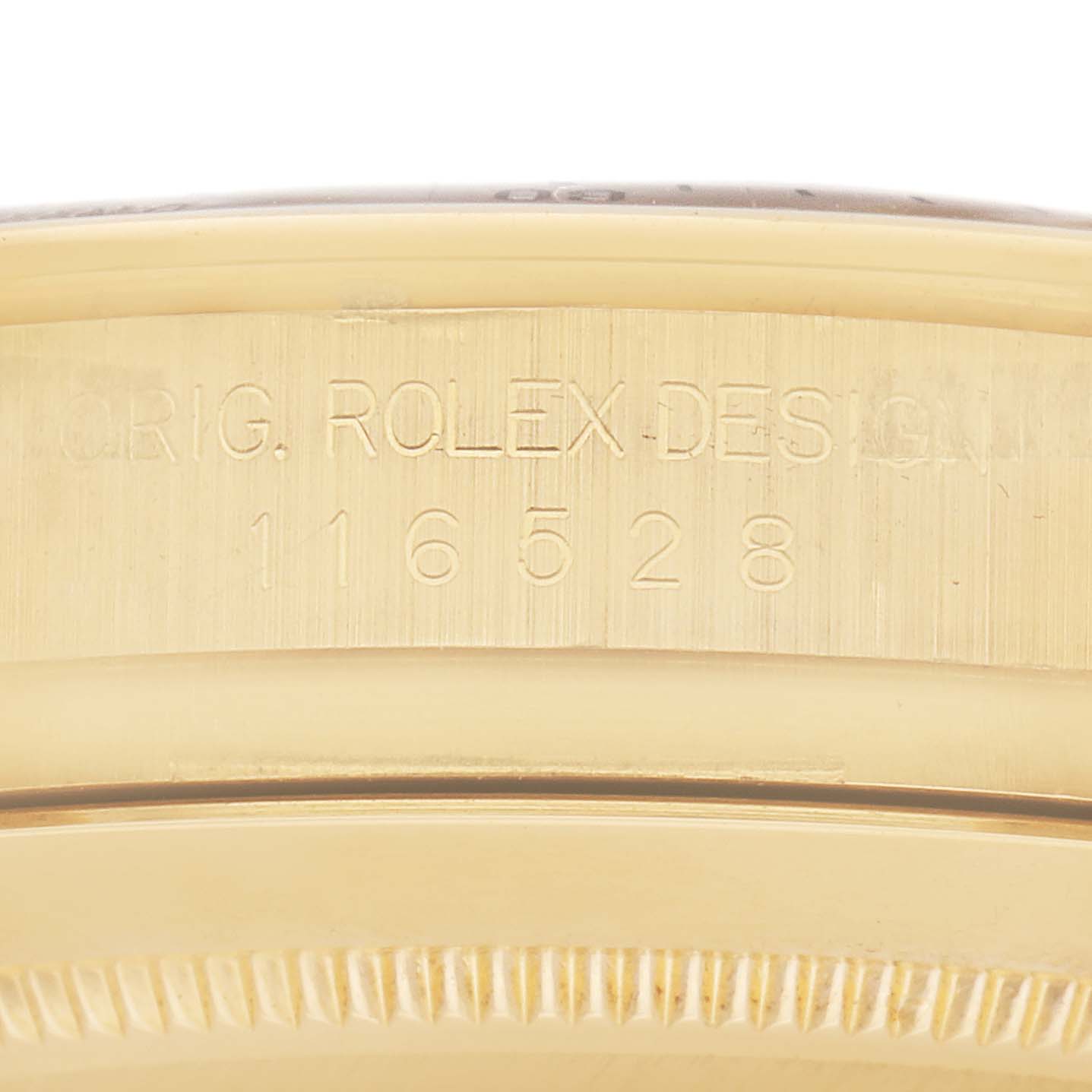 The image shows a close-up of the side of a Rolex Daytona 116528 Men
s Yellow Gold Black Dial 116528 Men
s Yellow Gold Black Dial watch, highlighting its engraved model number.