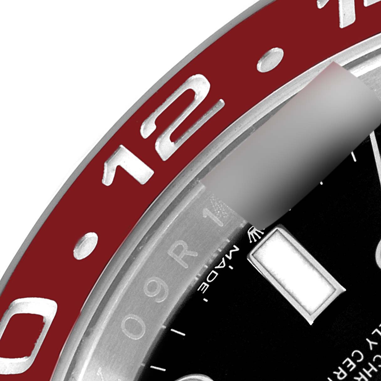 This close-up angle of a Rolex GMT-Master 126710 Men's Stainless Steel Black Dial 126710 Men's Stainless Steel Black Dial watch shows part of the red bezel, the "12" marker, and the edge of the black dial.