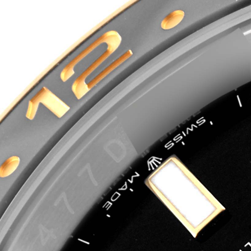 This close-up image of the Rolex GMT-Master 126713 Men's Steel and Gold (two tone) Black Dial 126713 Men's Steel and Gold (two tone) Black Dial watch shows the bezel with the "12" marker, part of the dial, and the "Swiss Made" text.