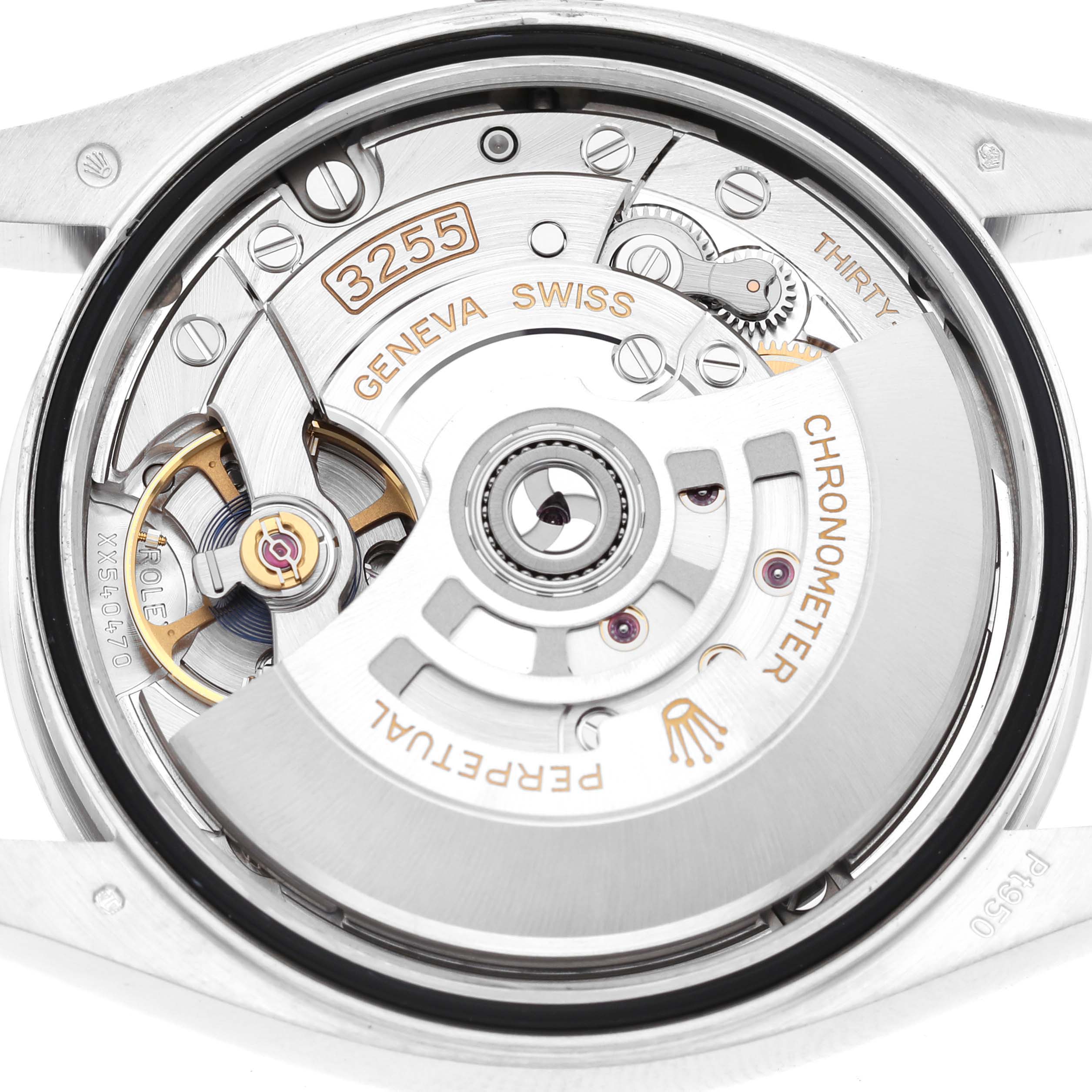 The image shows a close-up of the movement of a Rolex President 128236 Men's Platinum Black Dial model watch, highlighting gears and engravings.