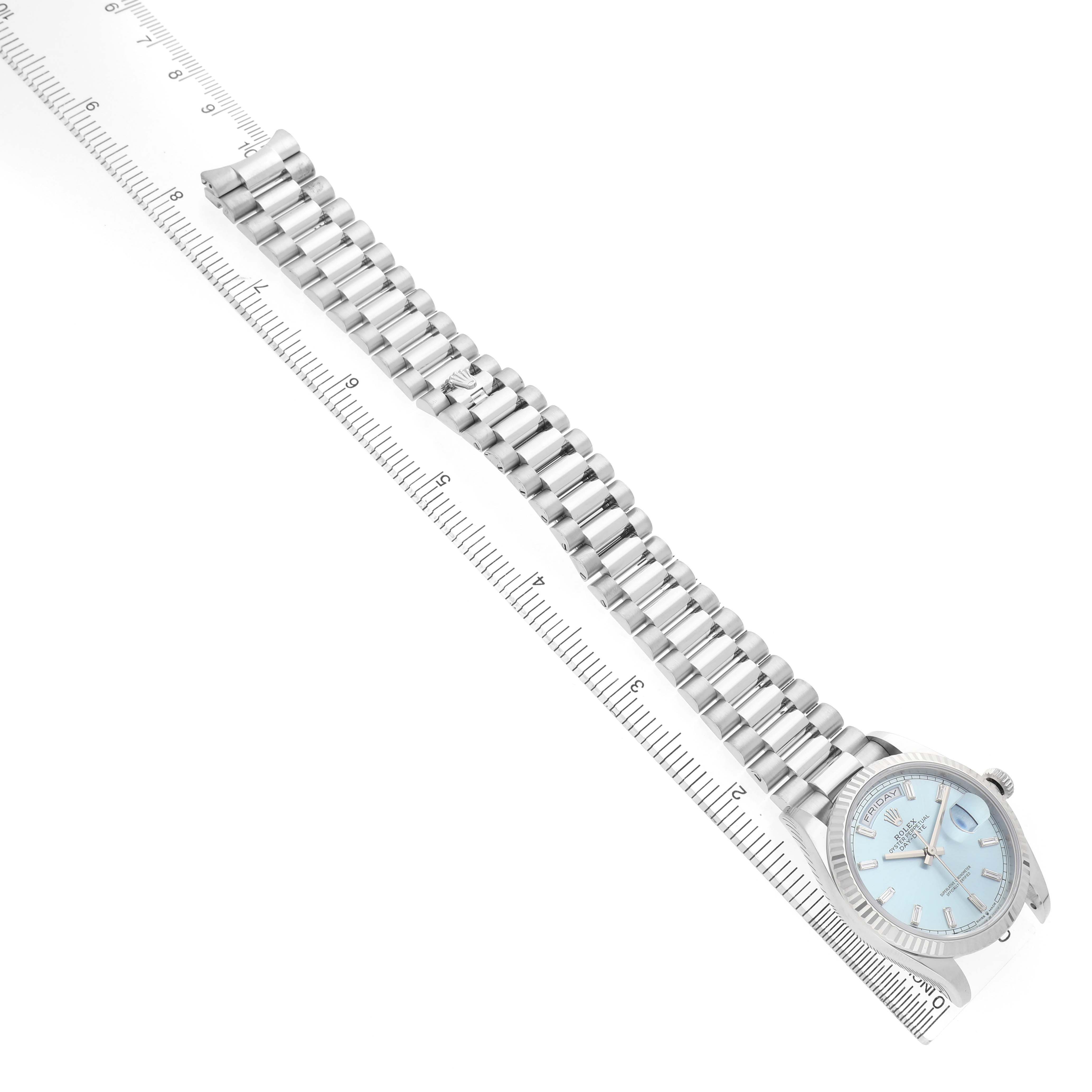 The Rolex President 128236 Men's Platinum Black Dial model watch is shown from an angled top view, displaying its face, clasp, and bracelet against a measuring ruler.