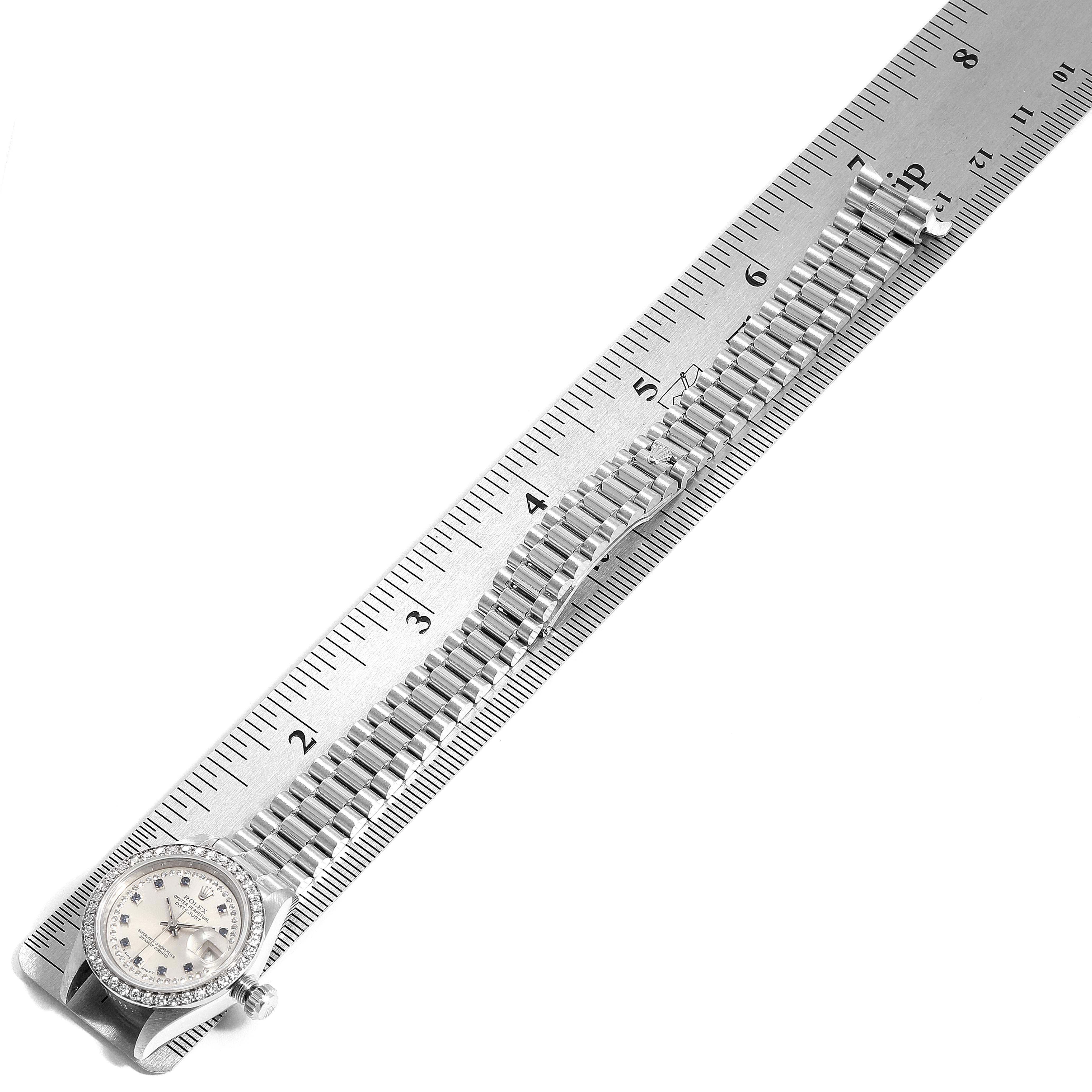 The image shows a top view of a Rolex President 69136 Women
s Platinum Silver Dial 69136 Women
s Platinum Silver Dial model watch with a ruler alongside, displaying the watch band and face.