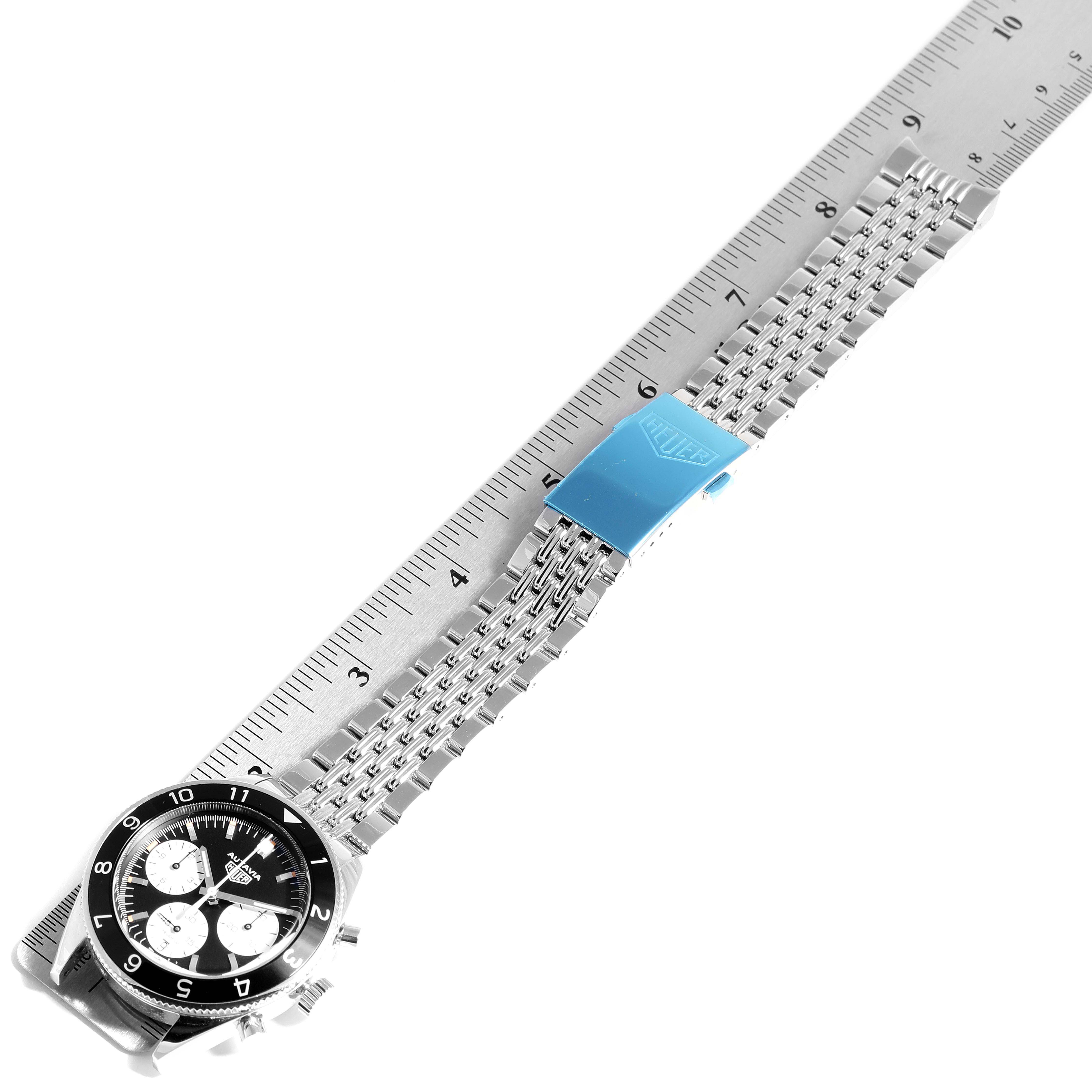 The image shows an Autavia model by Tag Heuer placed diagonally with the full watch and stainless steel band visible next to a ruler.