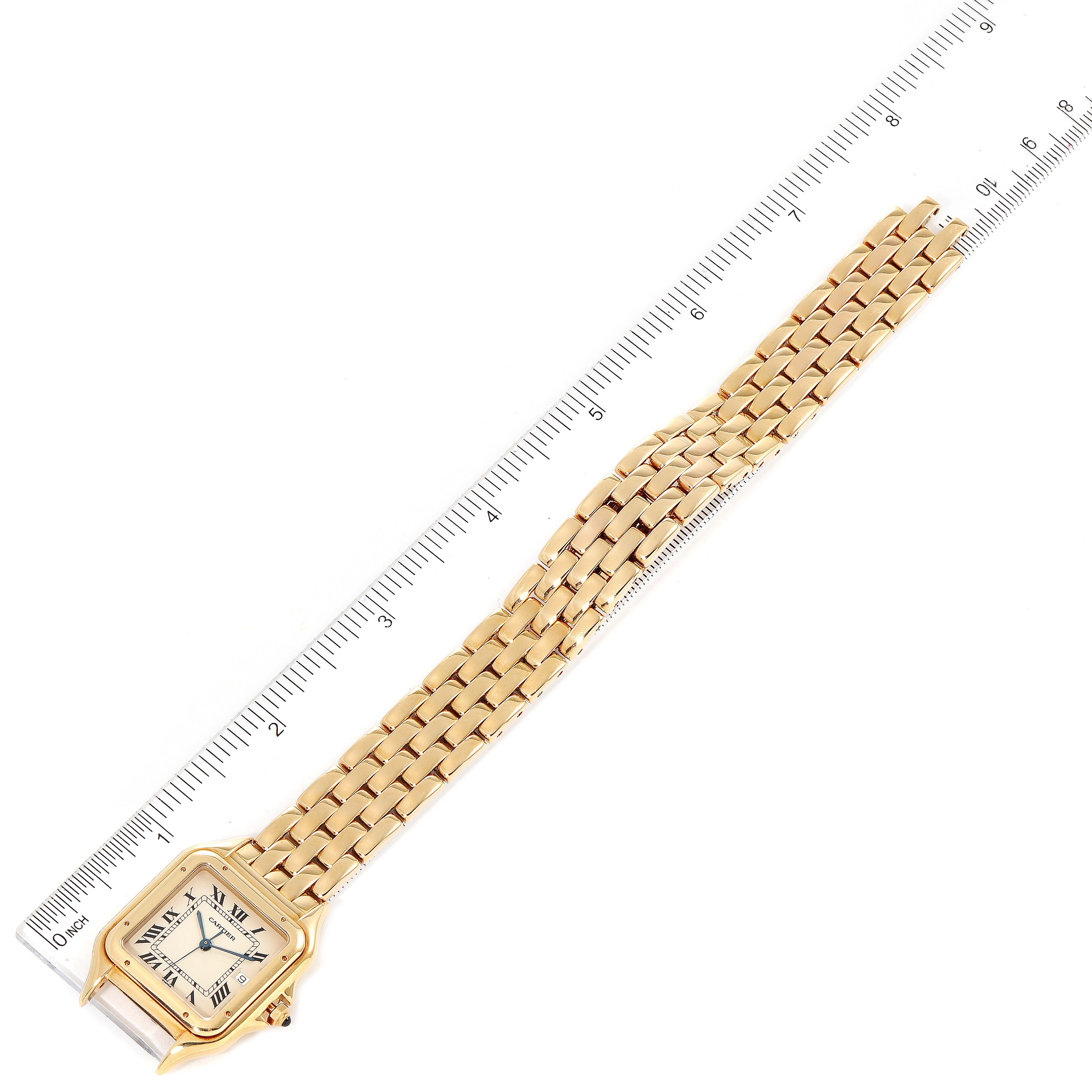 This image shows a top view of a Cartier Panthere W25014B9 Men
s Yellow Gold Silver Dial W25014B9 Men
s Yellow Gold Silver Dial watch with a gold bracelet placed alongside a ruler for scale.