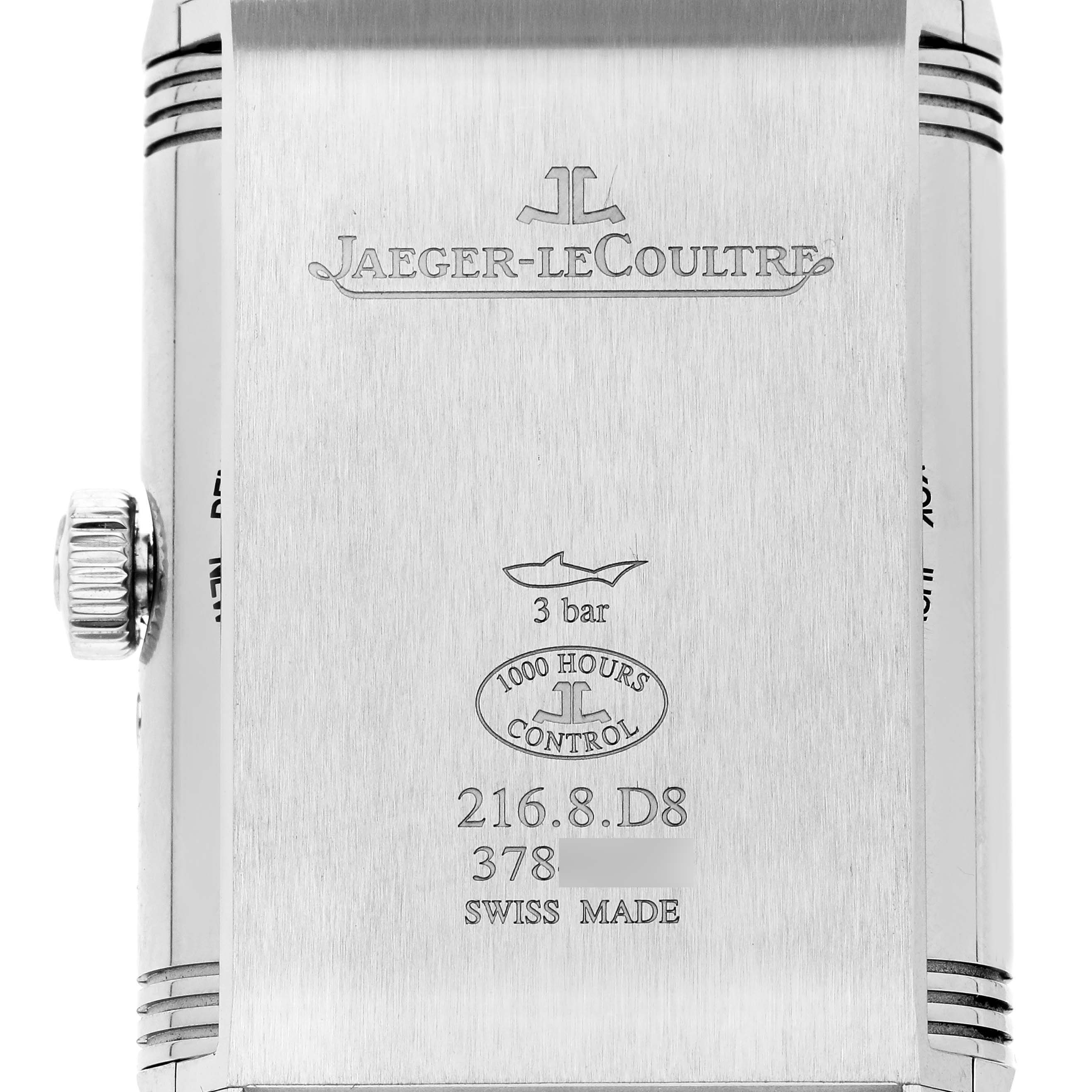 The image shows the back of a Jaeger-LeCoultre Reverso watch, including the crown and engraved details.