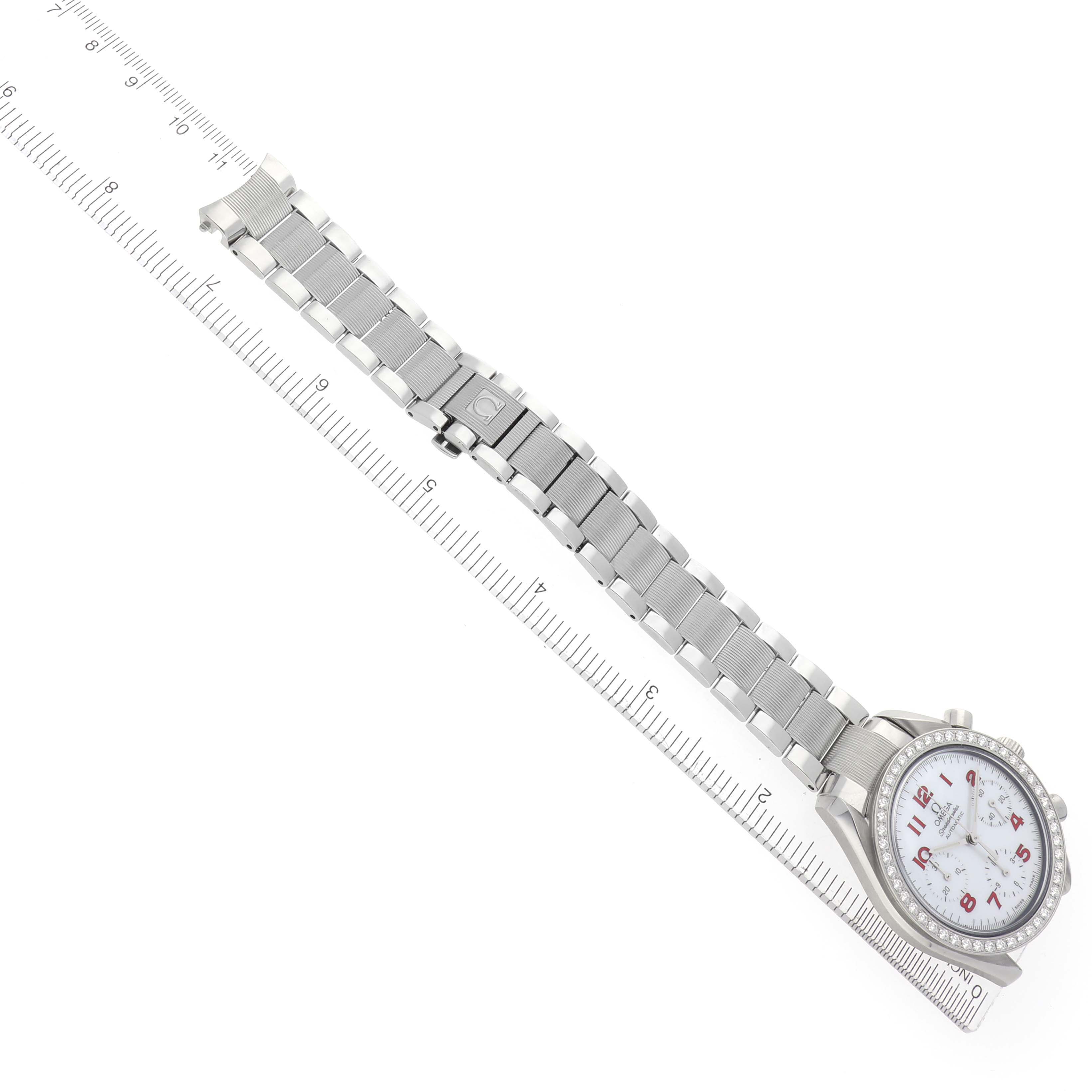 The Omega Speedmaster 3515.79.00 Men
s Stainless Steel Mother of Pearl Dial 3515.79.00 Men
s Stainless Steel Mother of Pearl Dial watch is shown from a top-down angle, displaying its bracelet and partial dial next to a ruler.