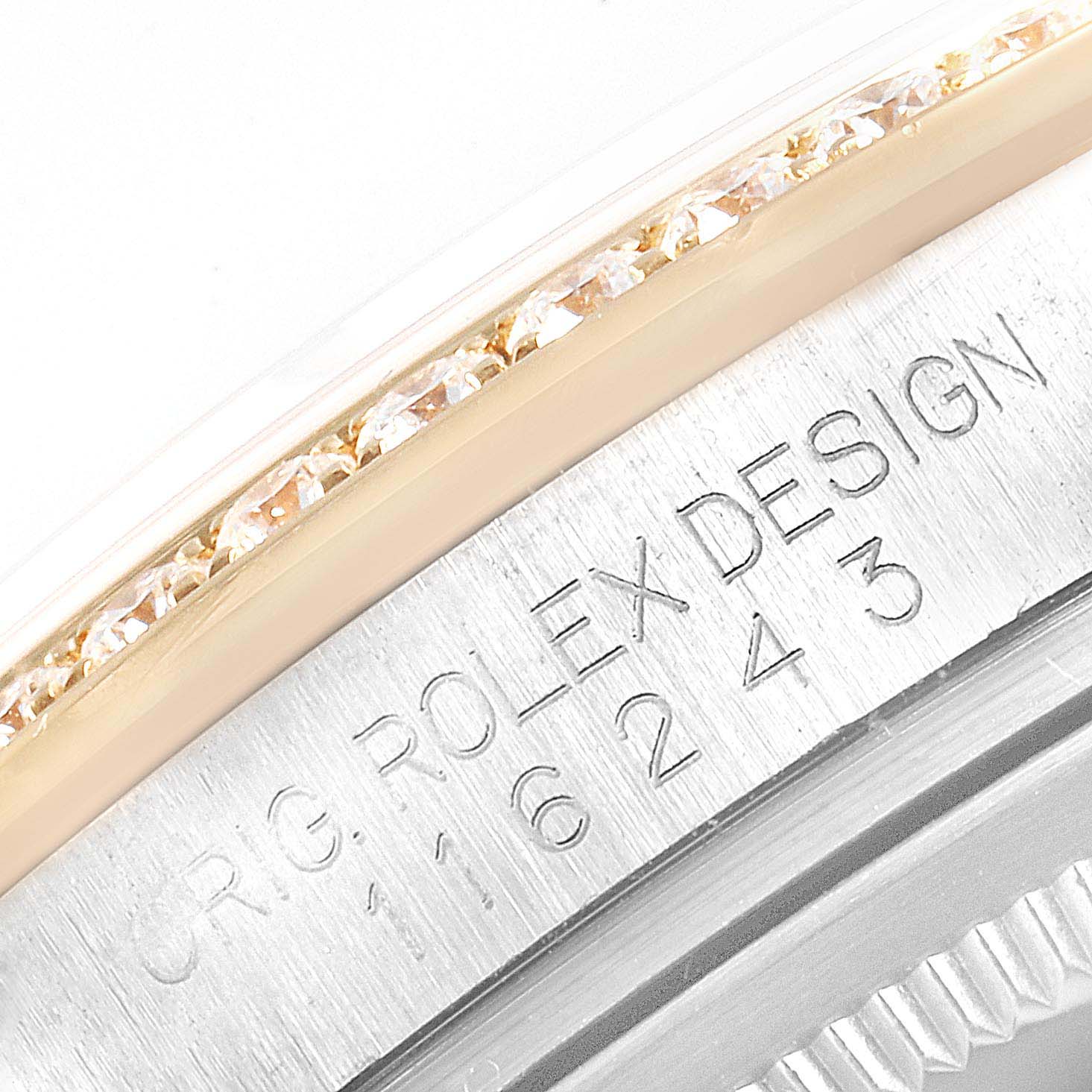 The image shows a close-up of the bezel and case side of a Rolex Datejust 116243 Men's Steel and Gold (two tone) Champagne Dial 116243 Men's Steel and Gold (two tone) Champagne Dial watch, featuring diamonds and engraved text.