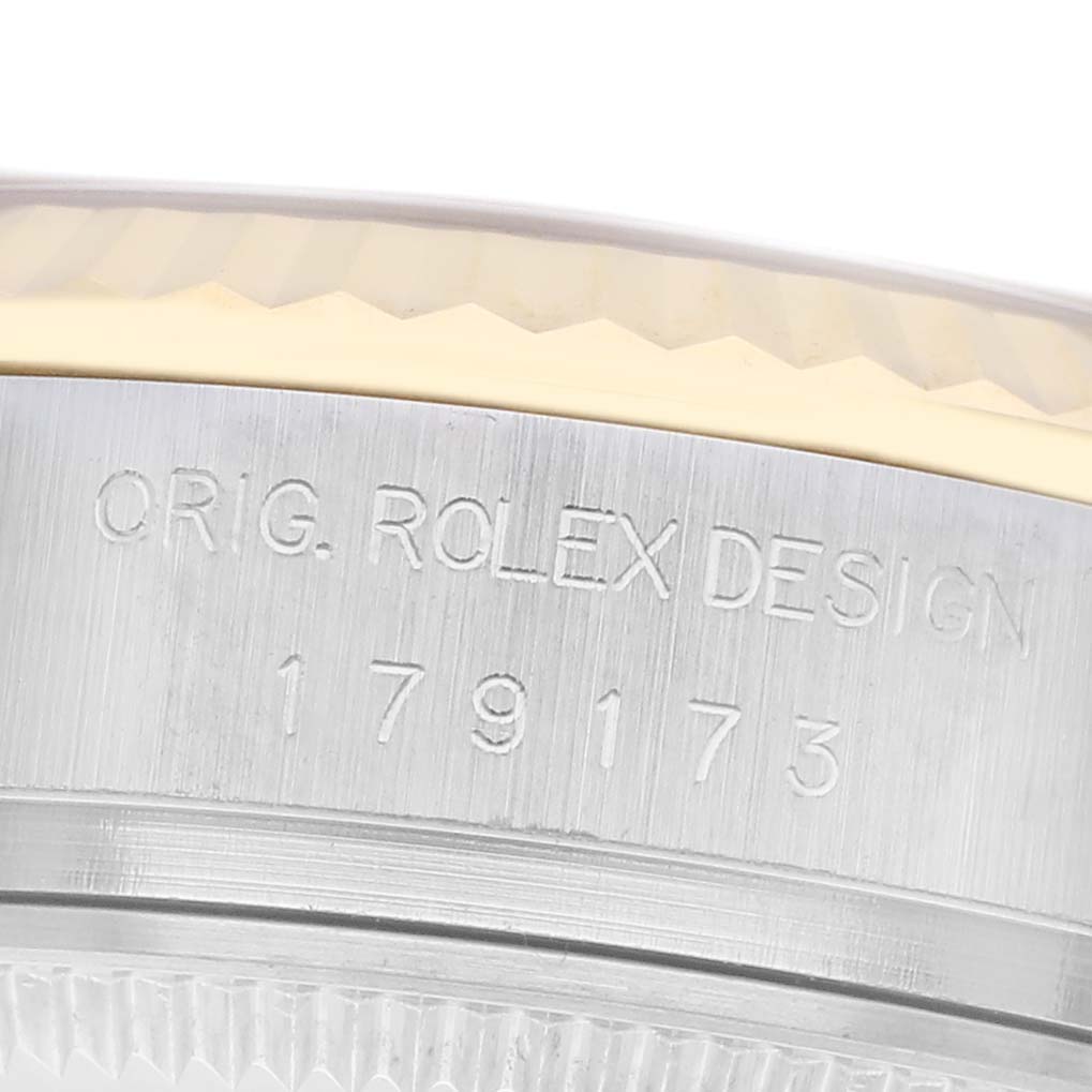 The image shows the side of a Rolex Datejust 179173 Women
s Steel and Gold (two tone) Champagne Dial 179173 Women
s Steel and Gold (two tone) Champagne Dial watch case, focusing on engraved text and part of the bezel.