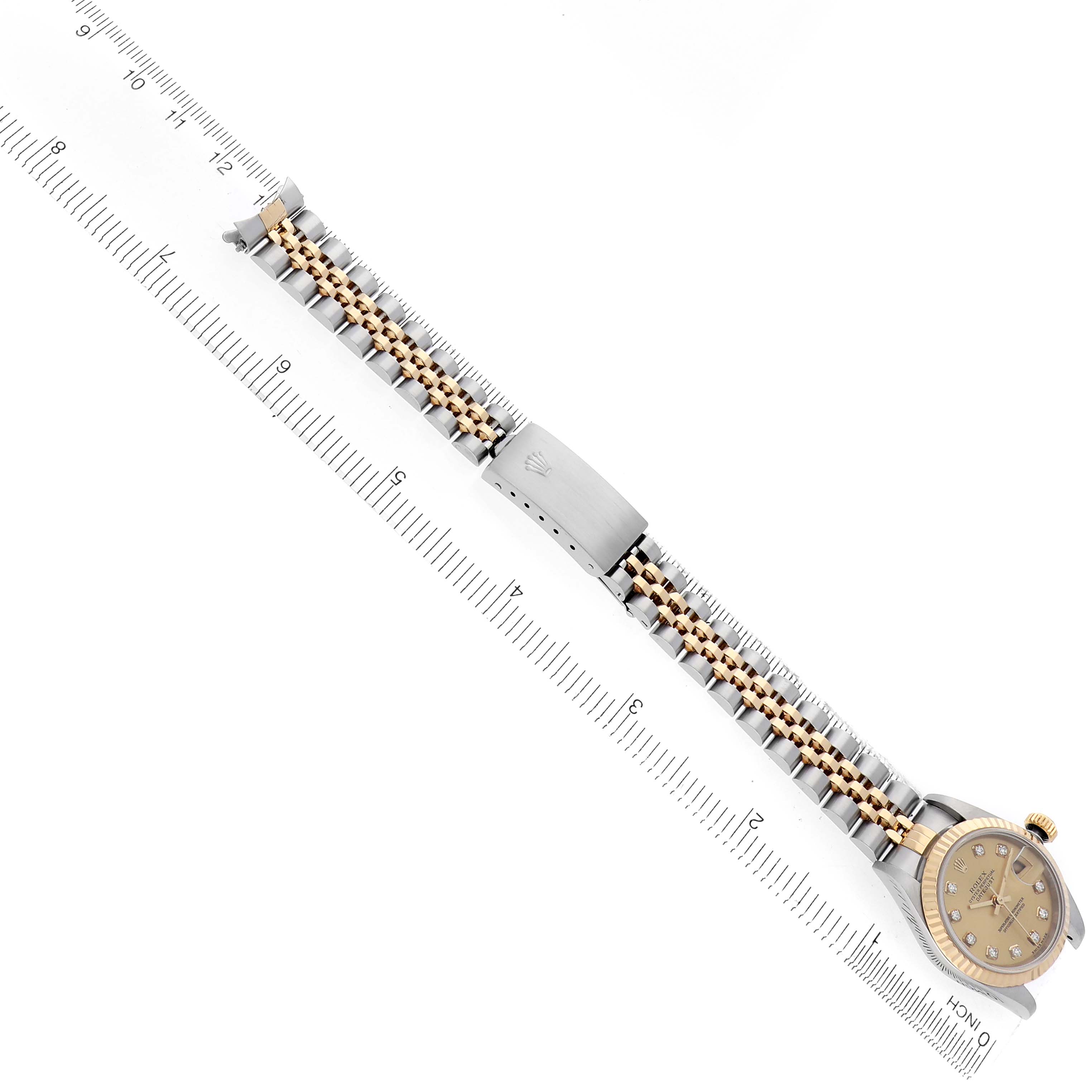 The image shows a Rolex Datejust 79173 Women
s Steel and Gold (two tone) Champagne Dial 79173 Women
s Steel and Gold (two tone) Champagne Dial watch from a top-down angle, displaying the full bracelet with a ruler for scale.