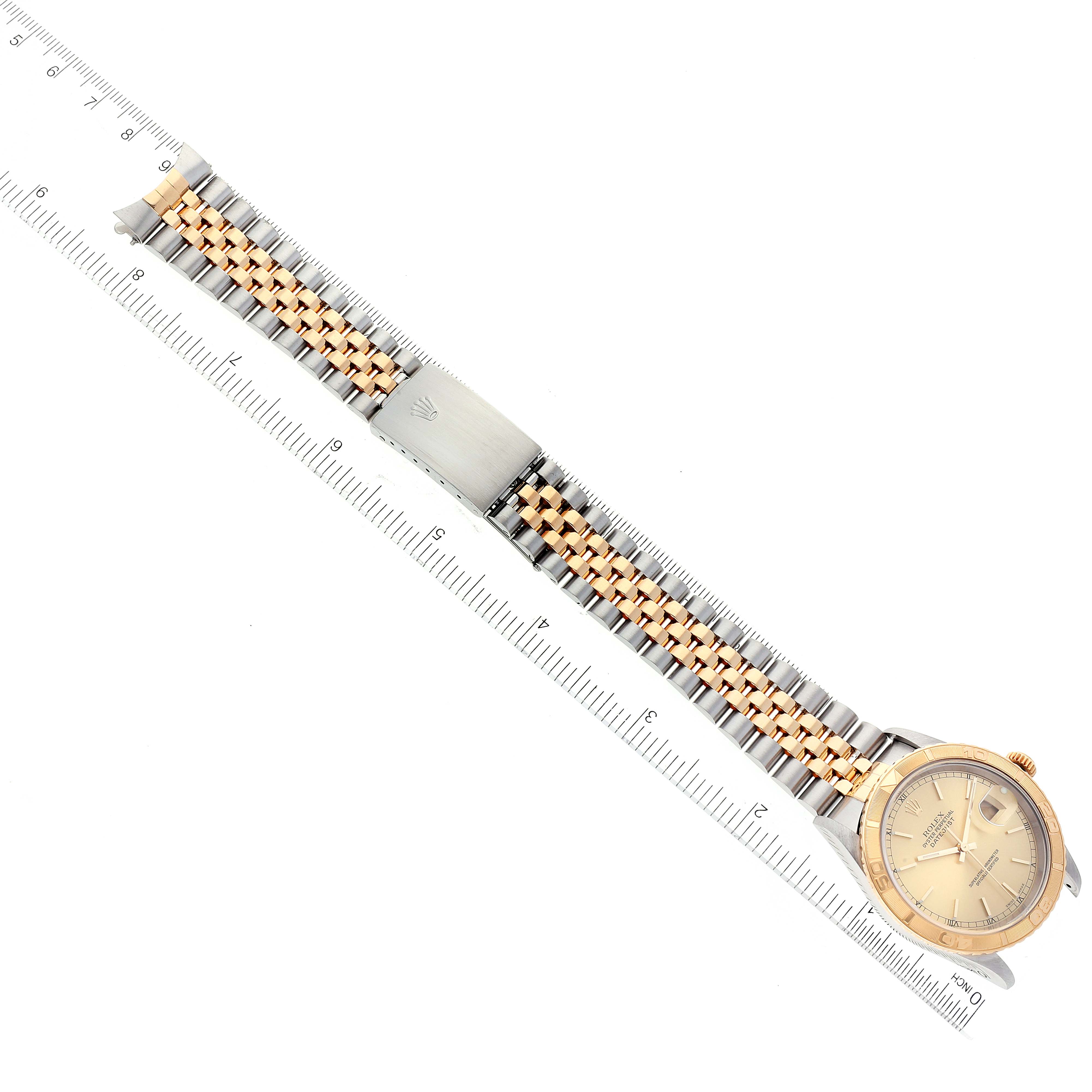 The image shows a Turn-o-Graph Rolex watch laid flat with a ruler for scale, displaying its dial, bezel, and bracelet.