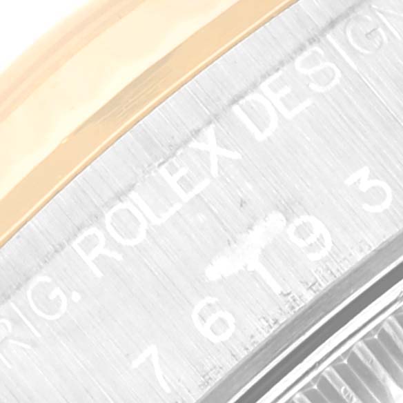 The image shows a close-up angle of the Rolex Oyster Perpetual 76193 Women's Steel and Gold (two tone) Black Dial 76193 Women's Steel and Gold (two tone) Black Dial model focusing on the bezel and part of the engraved design.