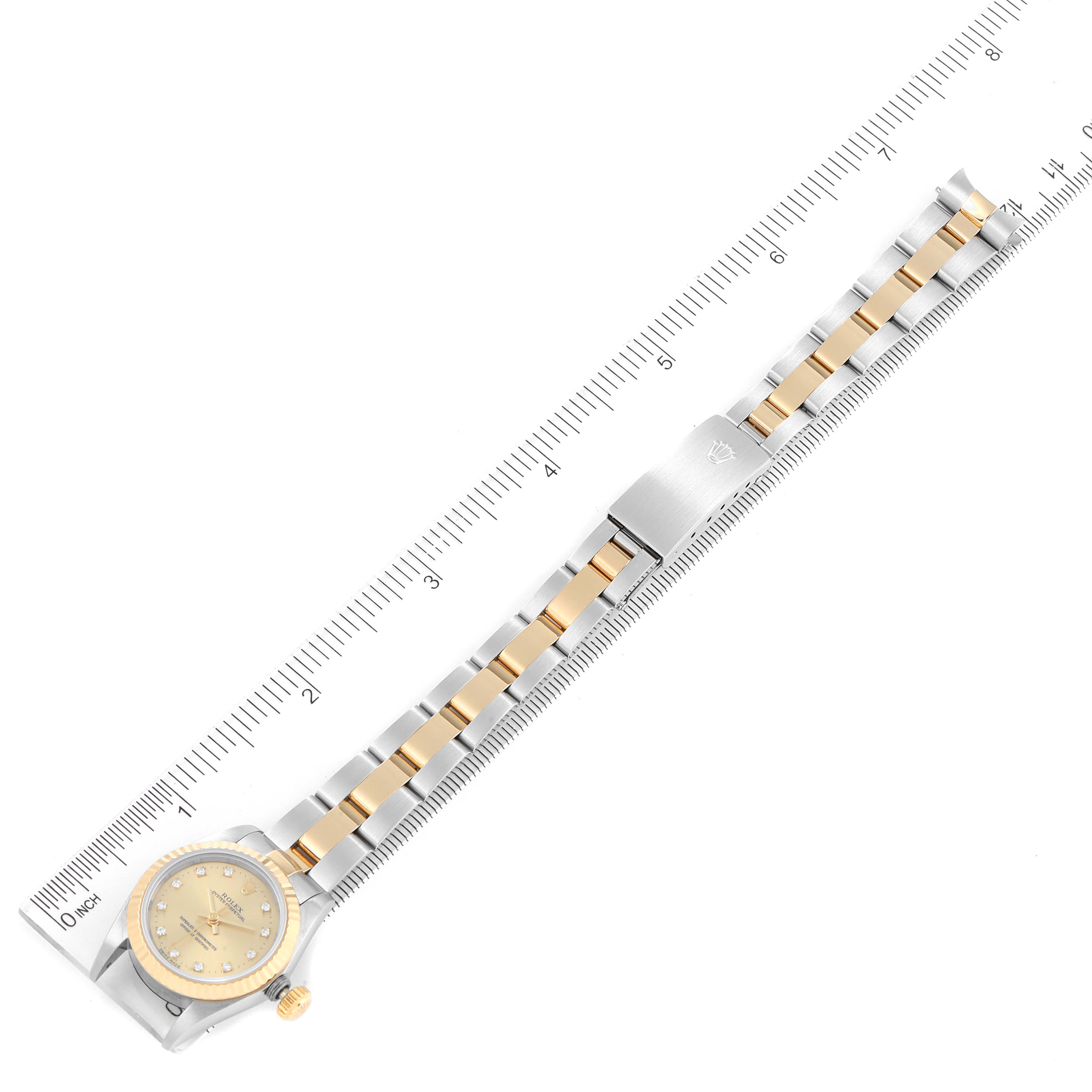 The image shows a top-down view of a Rolex Oyster Perpetual 67193 Women
s Steel and Gold (two tone) Champagne Dial 67193 Women
s Steel and Gold (two tone) Champagne Dial watch with its full band and clasp laid against a ruler for scale.