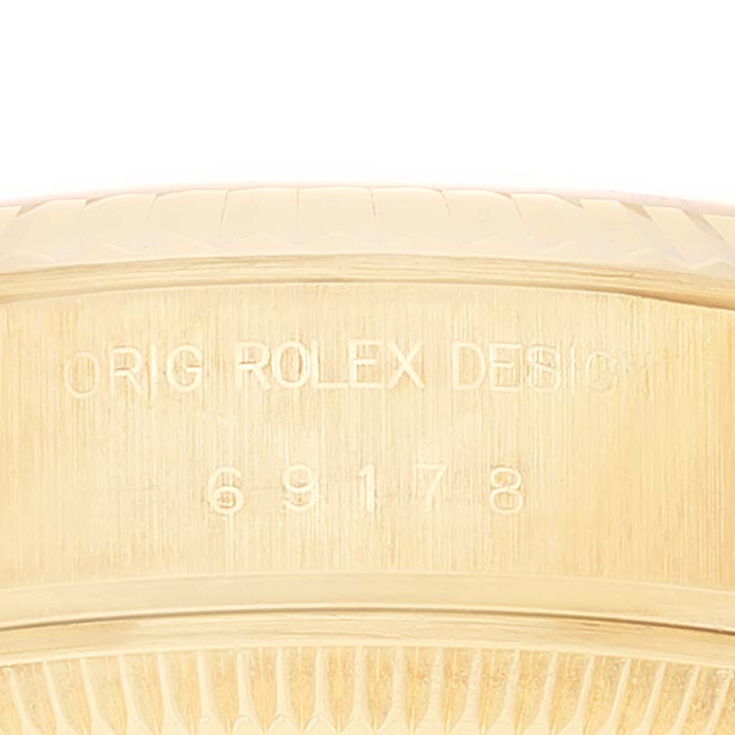 The image shows an angled close-up of a Rolex President 69178 Women
s Yellow Gold Champagne Dial 69178 Women
s Yellow Gold Champagne Dial model, focusing on the engraved markings of the bezel.