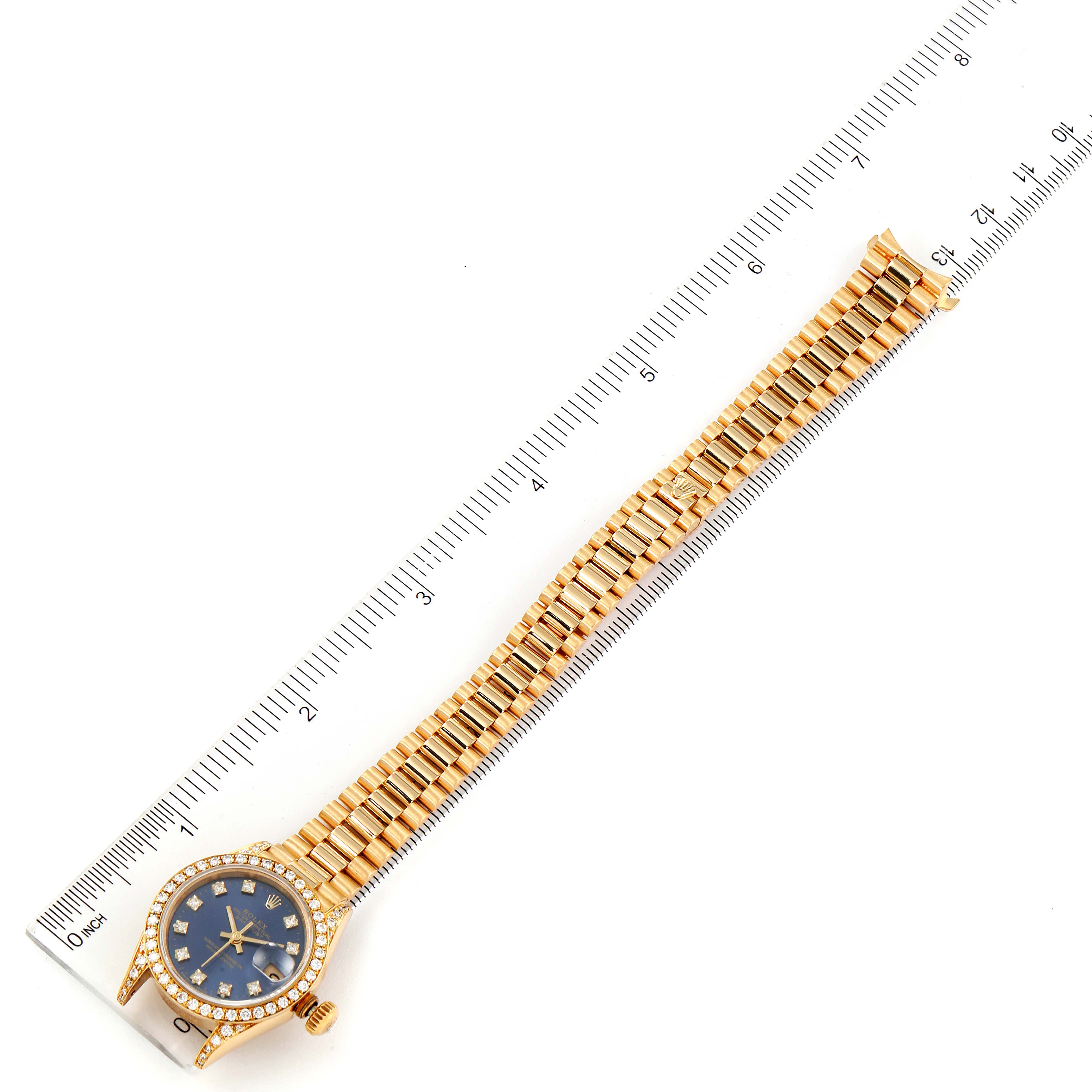 The Rolex President 69158 Women's Yellow Gold Blue Dial 69158 Women's Yellow Gold Blue Dial model watch is shown from a top-down angle, displaying the face, bezel, and full bracelet alongside a ruler.